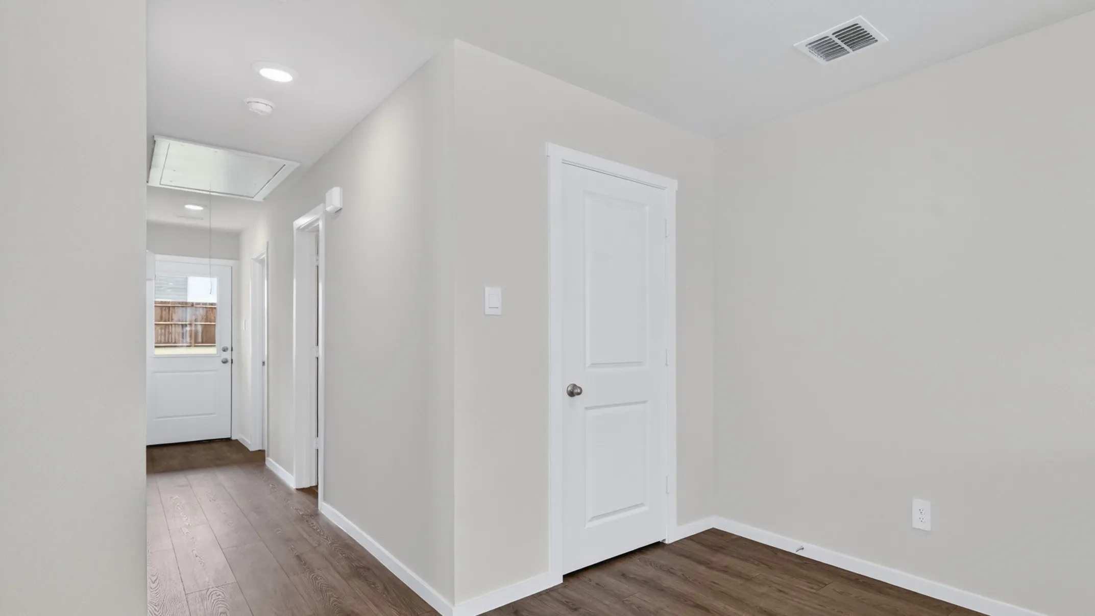Hallway featuring wood-finish flooring, recessed lighting, and a white paneled door