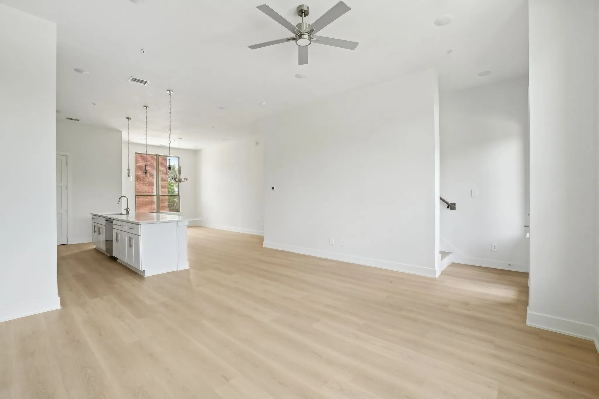 Unfurnished living room featuring light wood-style flooring, ceiling fan, and stairway