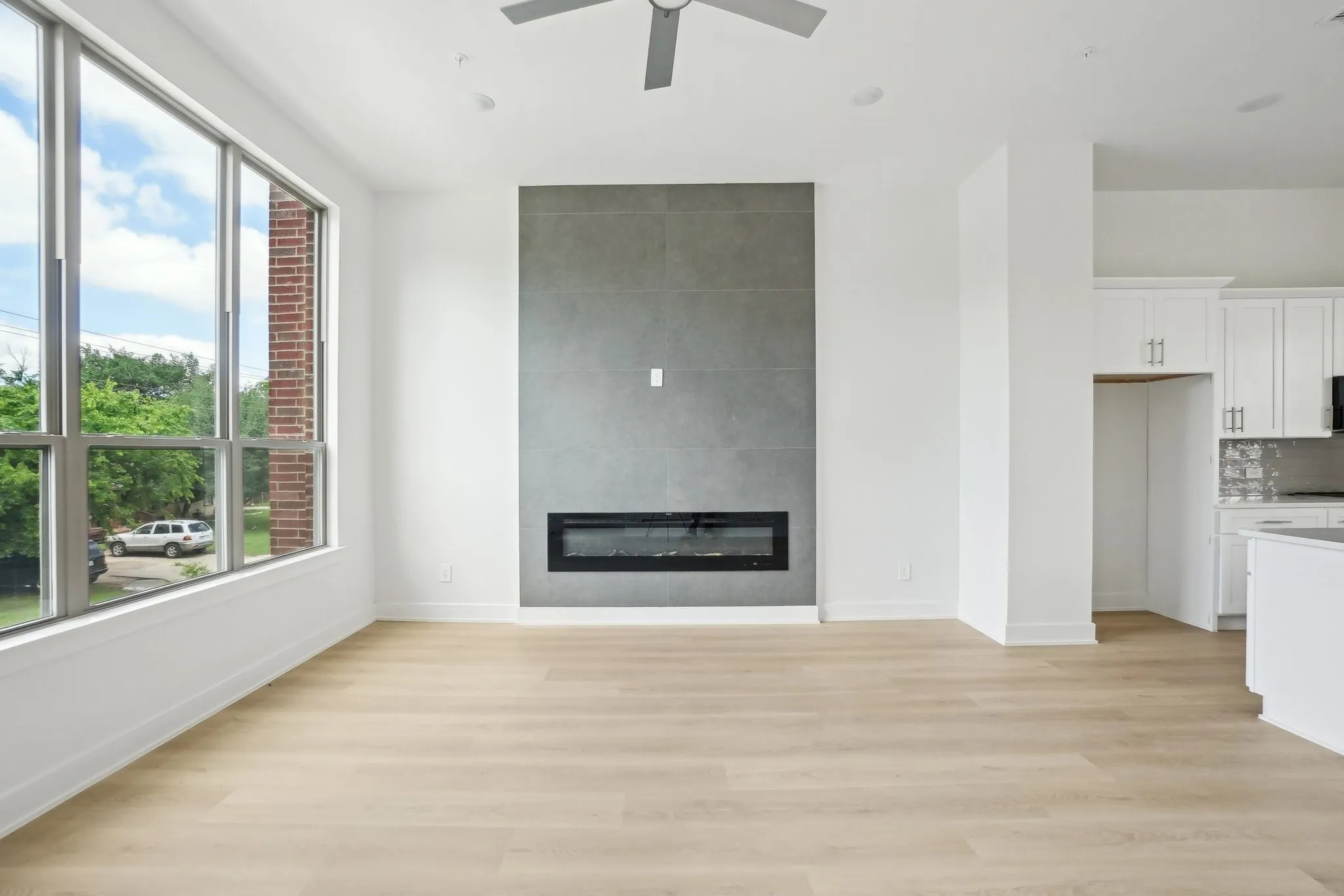 Unfurnished living room featuring light wood finished floors, a large fireplace, and ceiling fan