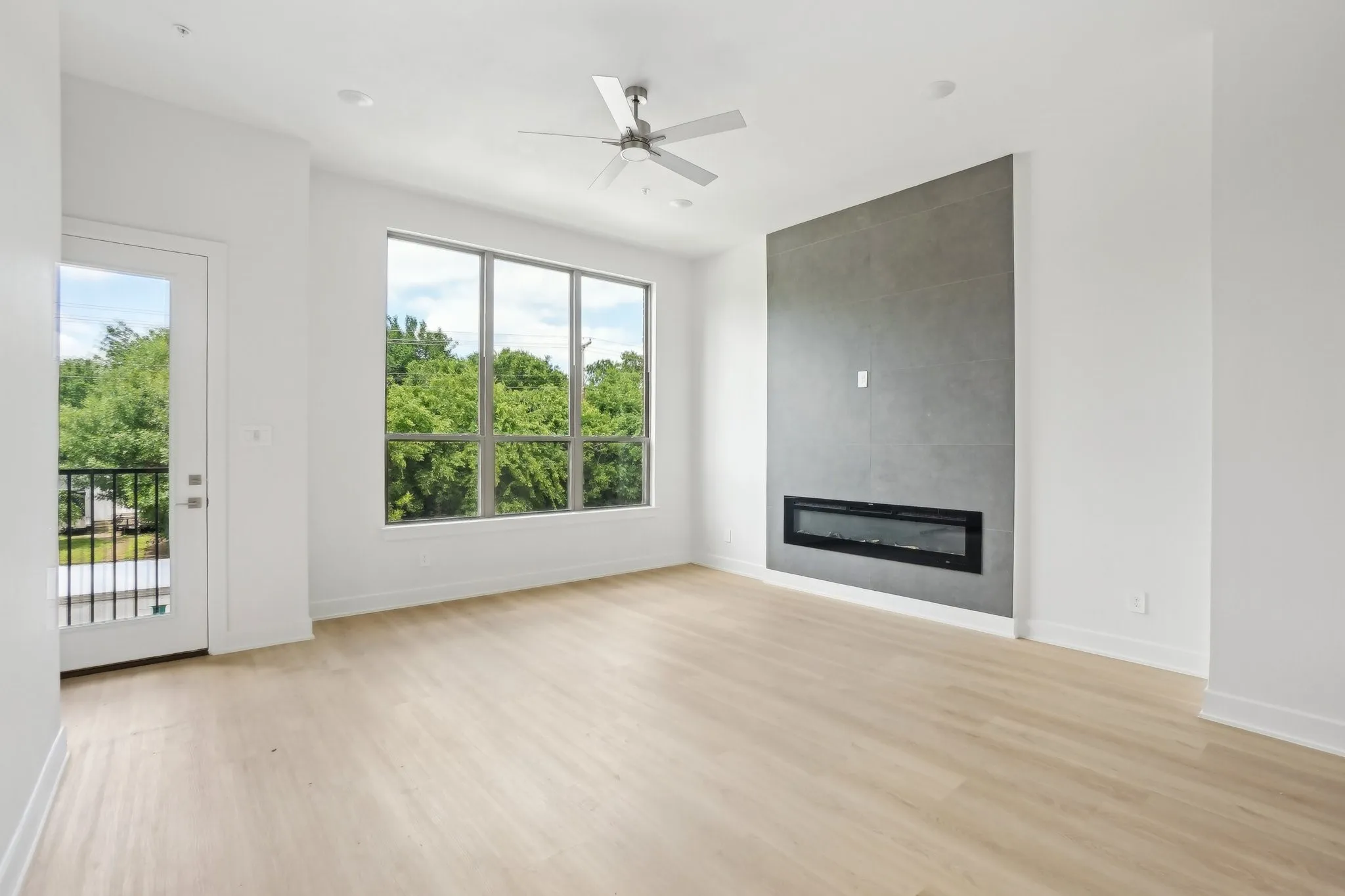 Unfurnished living room with a tile fireplace, light wood-style floors, and ceiling fan