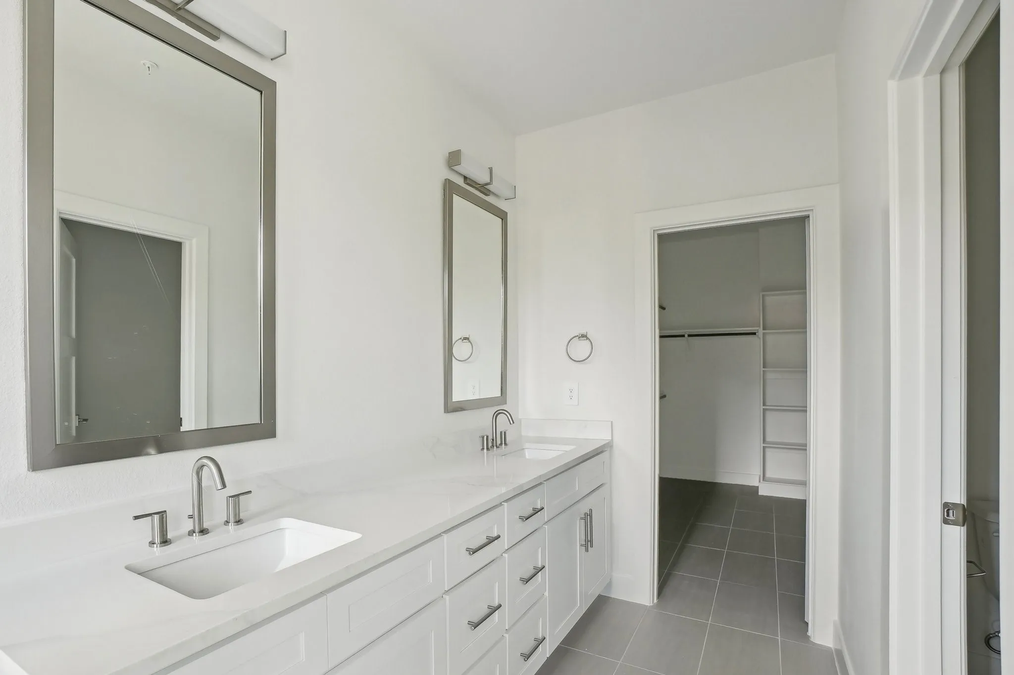 Bathroom featuring double vanity, a spacious closet, and light tile patterned floors
