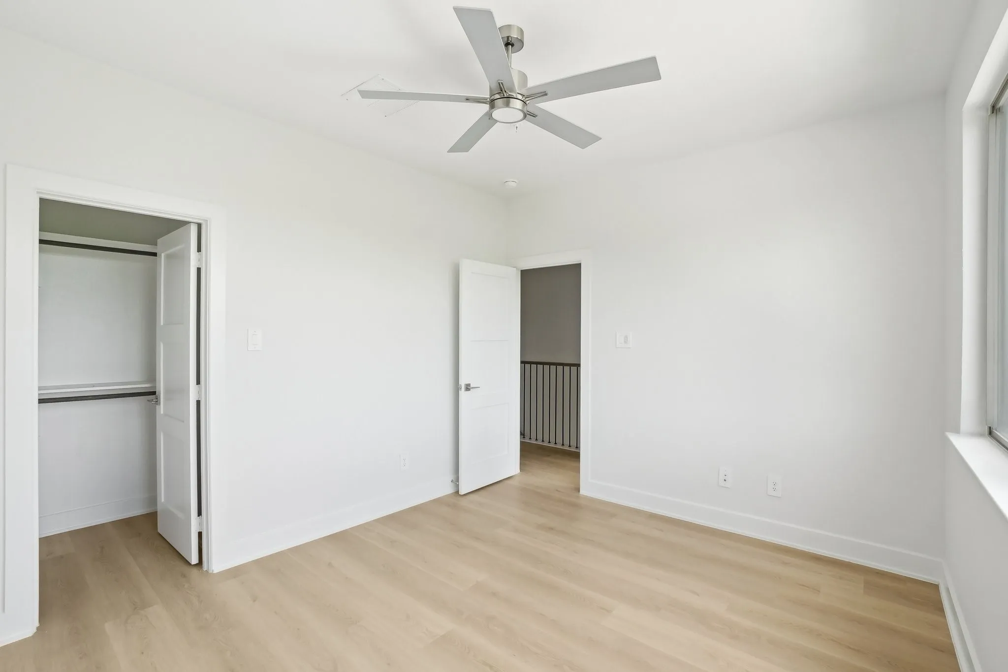 Unfurnished bedroom with light wood finished floors, a ceiling fan, and a spacious closet