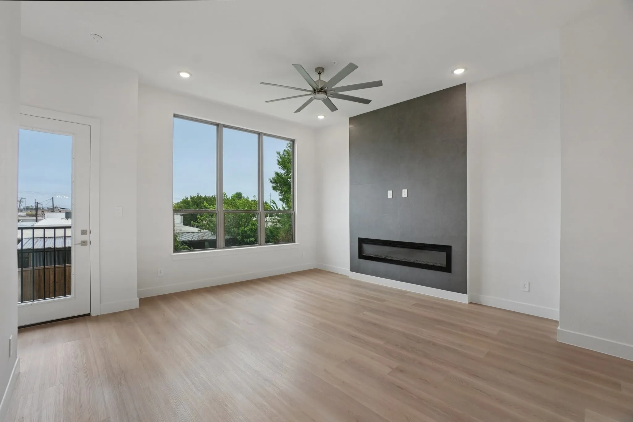 Unfurnished living room featuring light wood-type flooring, a large fireplace, recessed lighting, and a ceiling fan