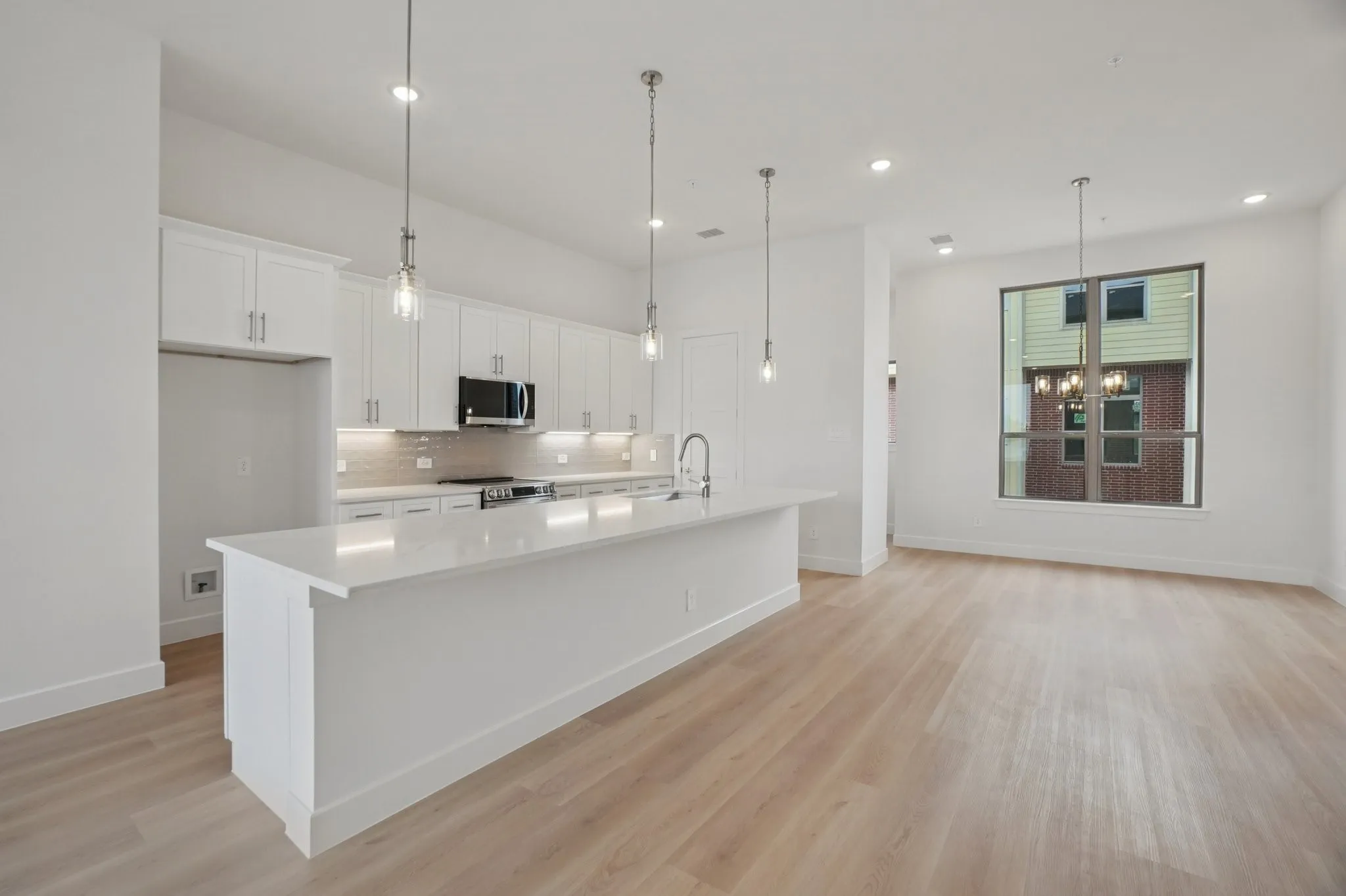 Kitchen featuring white cabinetry, a large island, pendant lighting, light wood-style floors, and recessed lighting