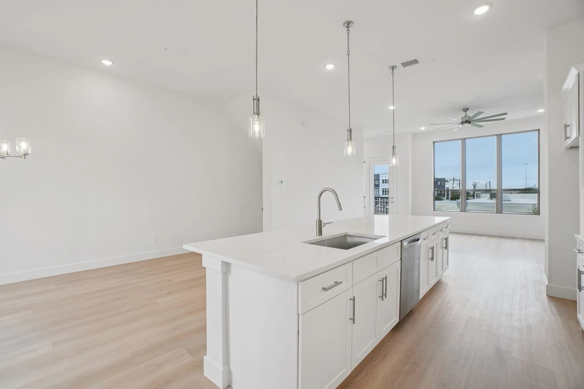 Kitchen with white cabinetry, open floor plan, a kitchen island with sink, decorative light fixtures, and light stone countertops
