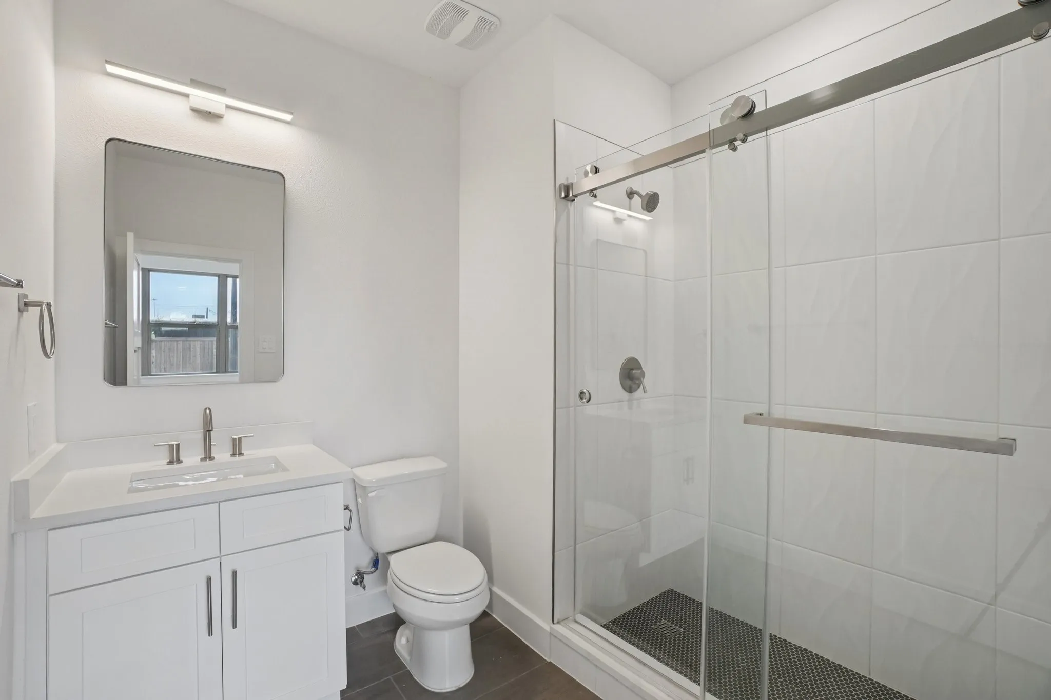 Bathroom featuring vanity, a stall shower, and dark tile patterned floors