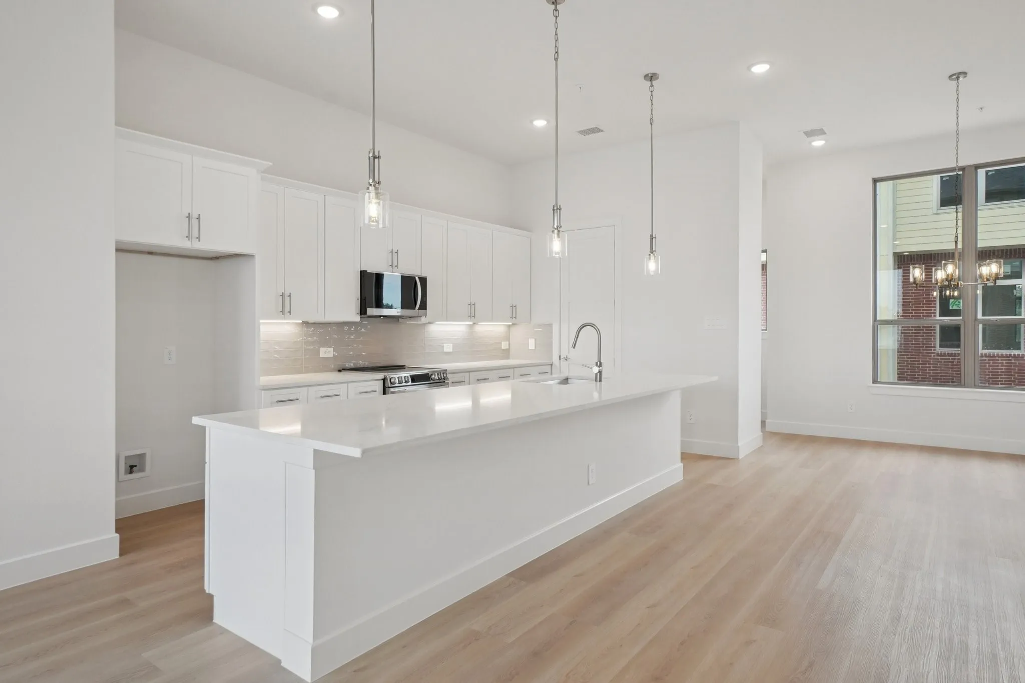 Kitchen with white cabinetry, a center island with sink, decorative light fixtures, light wood-style floors, and recessed lighting