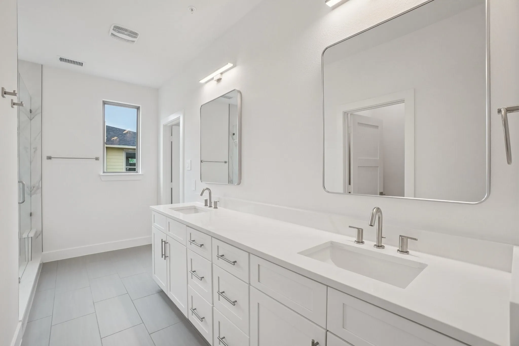 Full bathroom with double vanity, a marble finish shower, and light tile patterned floors
