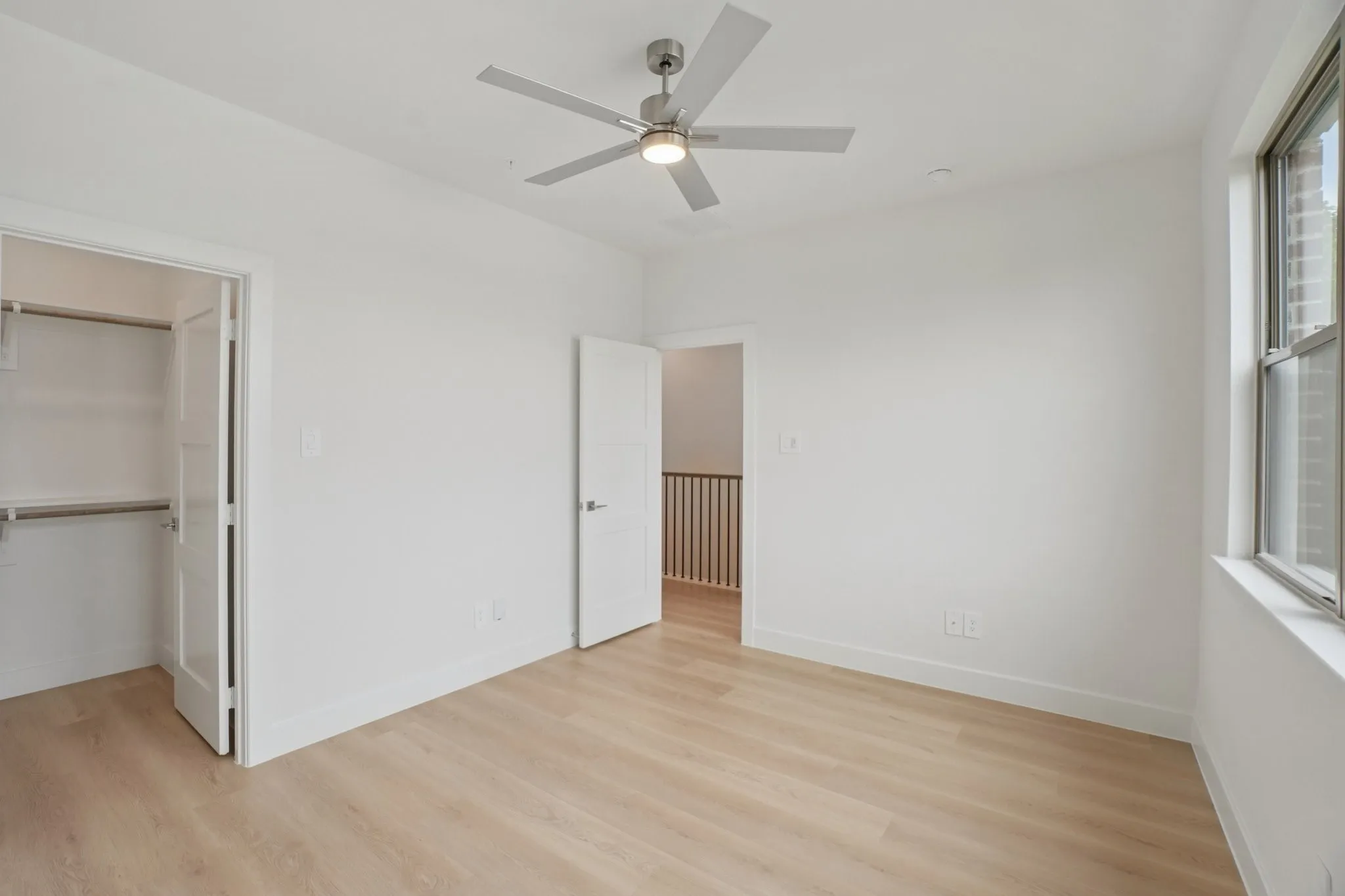 Unfurnished bedroom with light wood-style floors, a walk in closet, and a ceiling fan