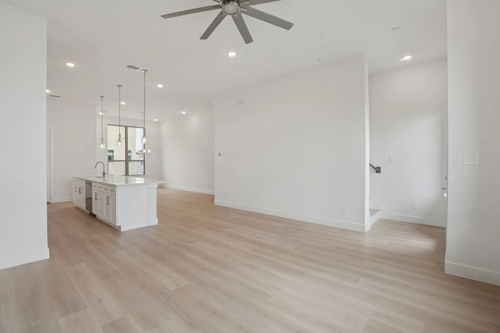 Unfurnished living room featuring light wood-style flooring, recessed lighting, ceiling fan, and stairs
