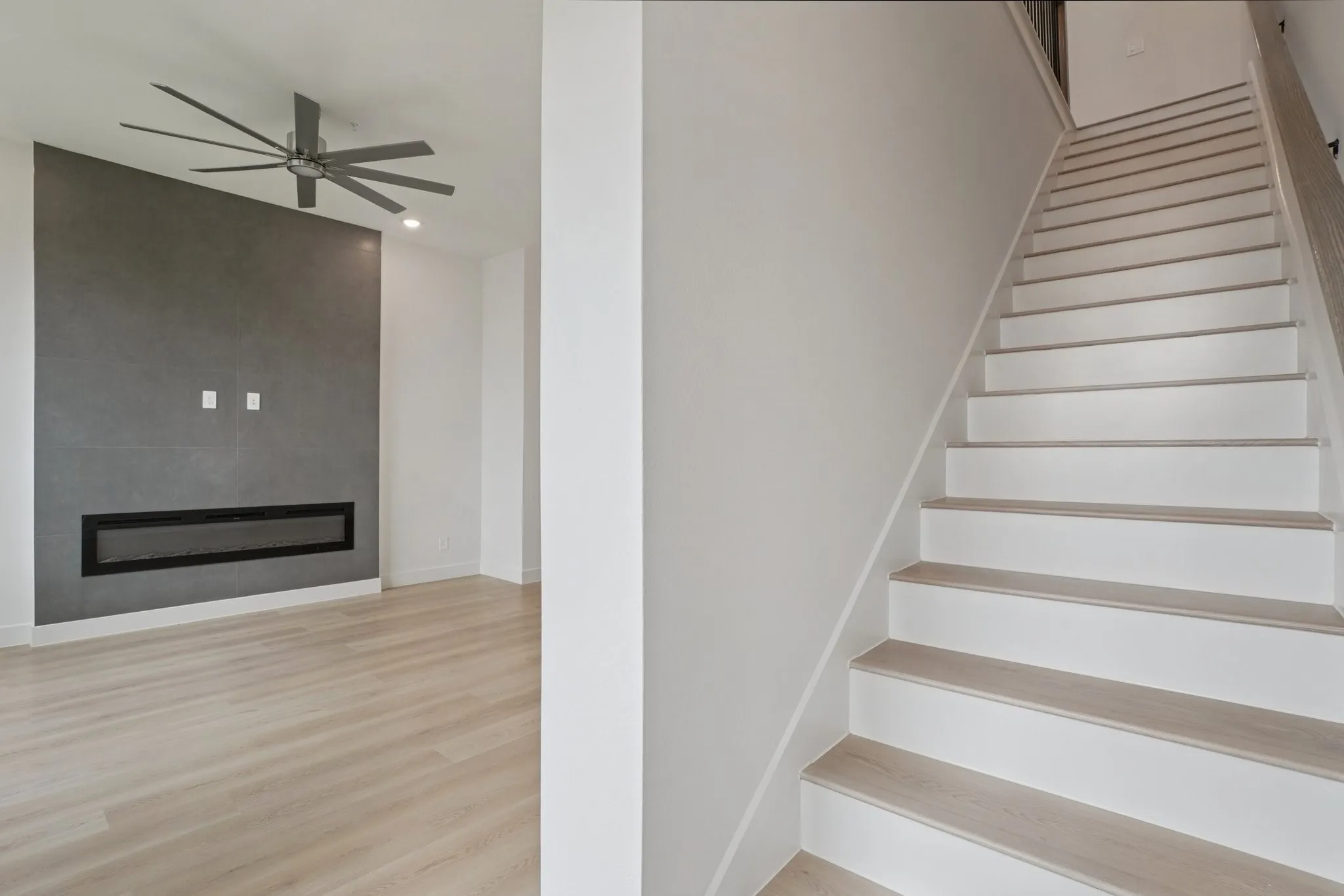 Stairway with a fireplace, wood finished floors, ceiling fan, and recessed lighting