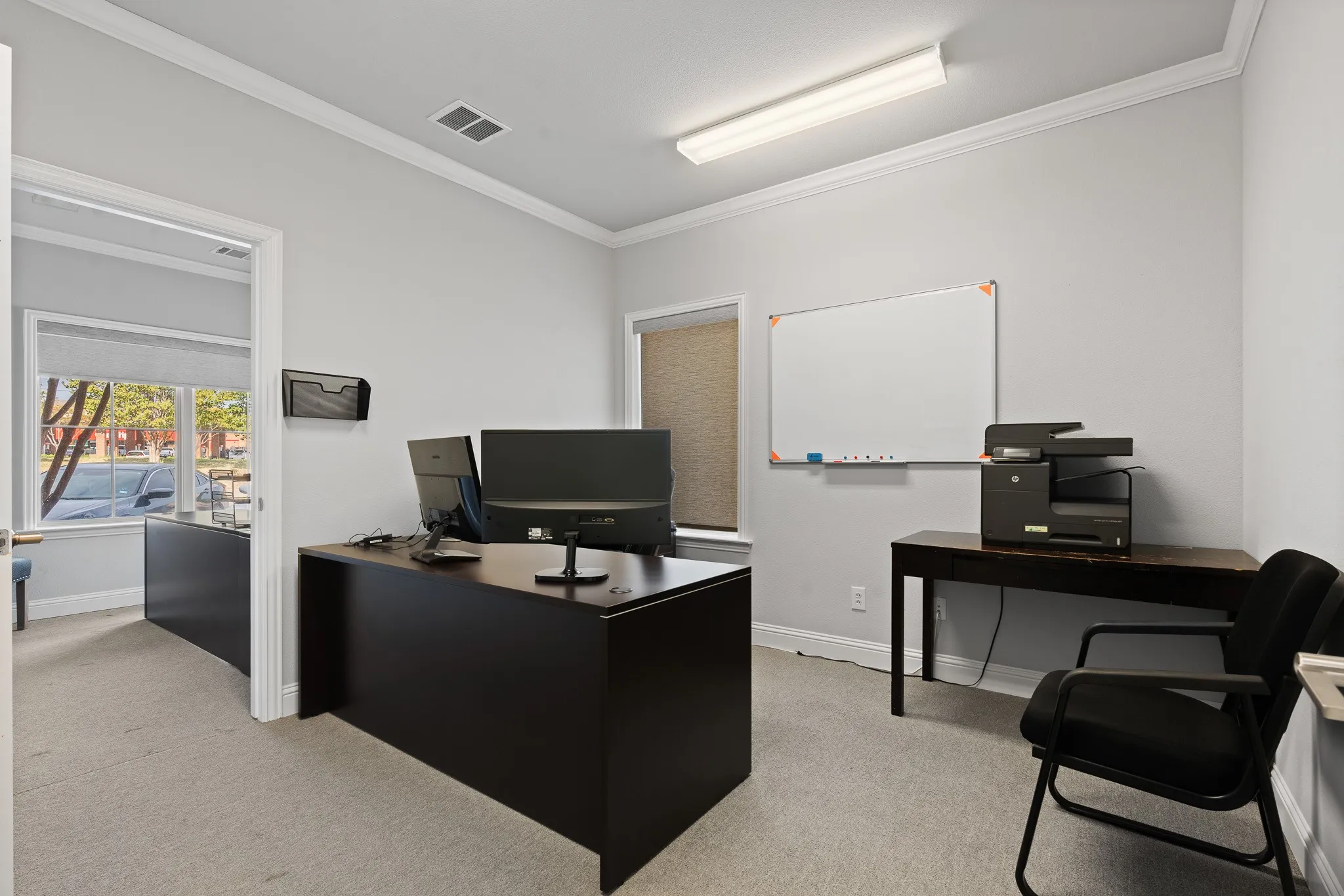 View of Front office with large windows overlooking the front of the building and frontage road, office right next to it with window that overlooks side of building