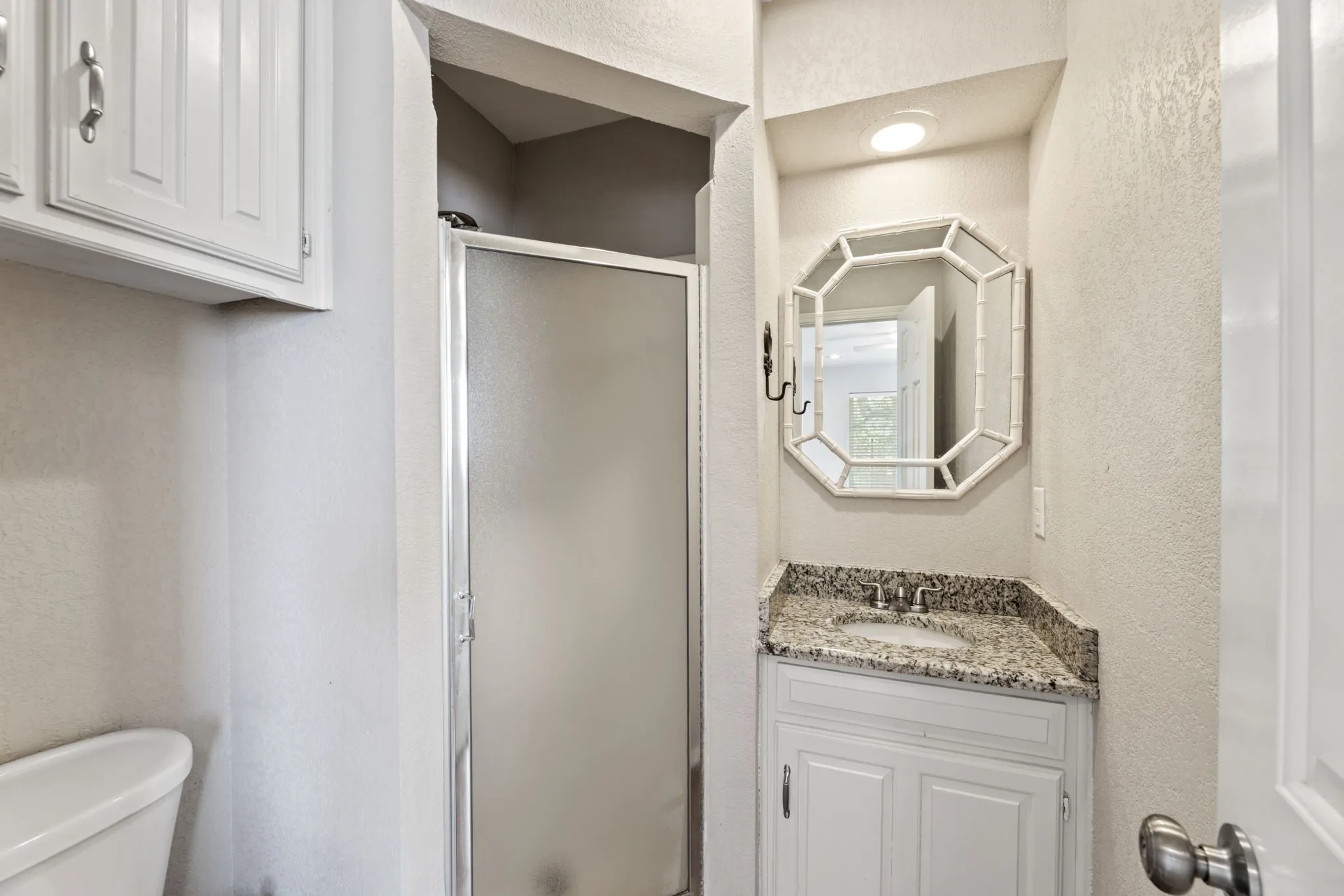 Bathroom featuring a textured wall, vanity, and a stall shower