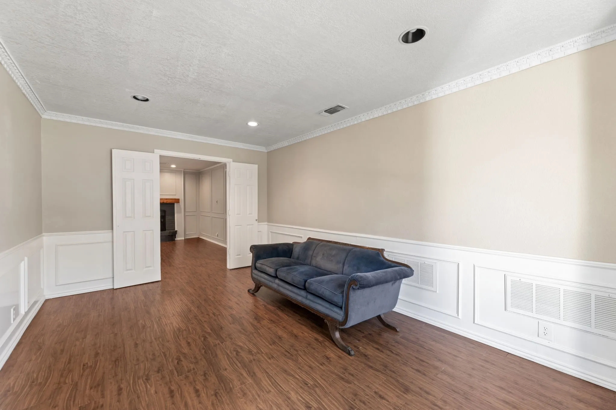 Living area with a wainscoted wall, a decorative wall, dark wood-type flooring, and a textured ceiling
