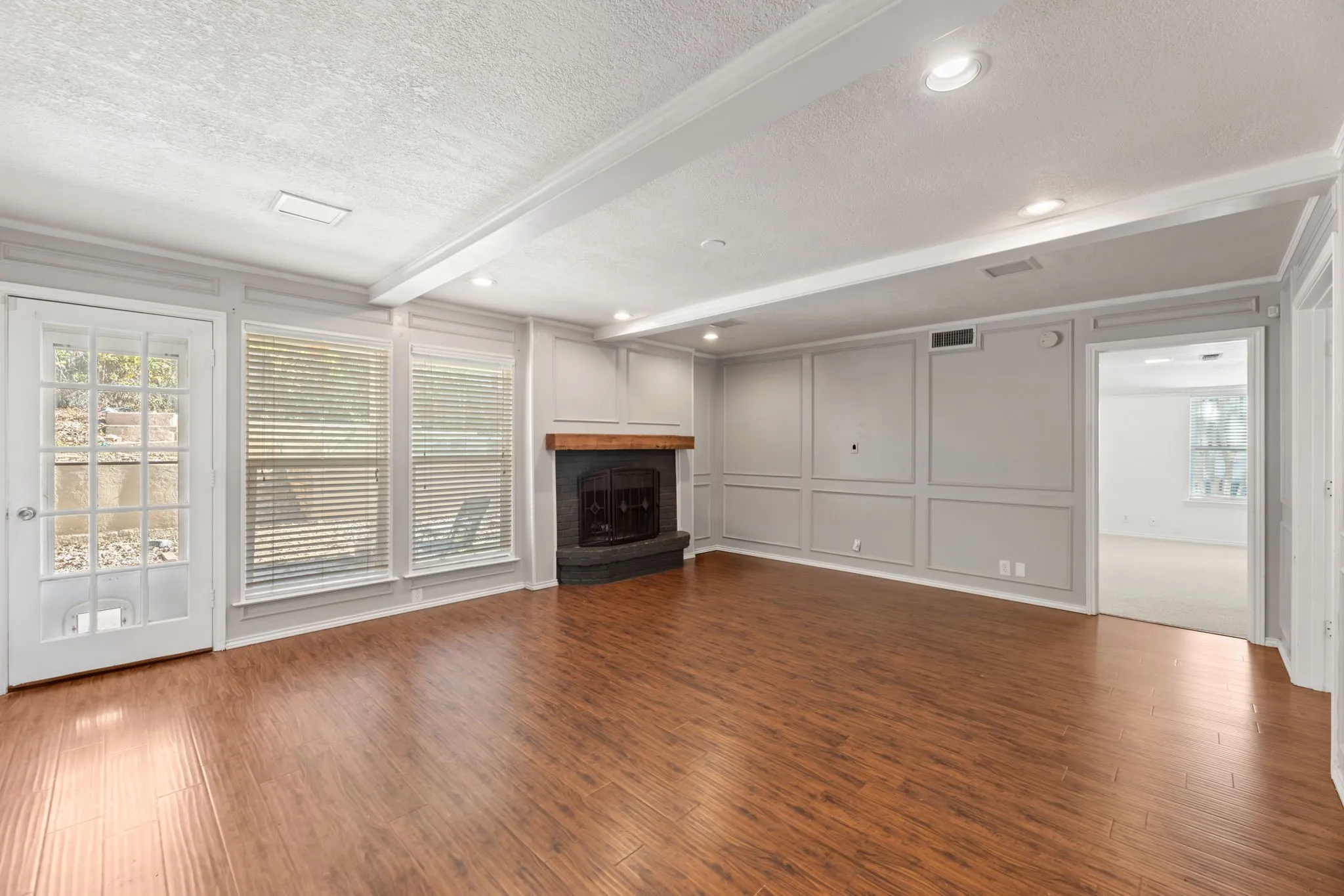Unfurnished living room featuring a decorative wall, healthy amount of natural light, a fireplace, dark wood-style floors, and a textured ceiling