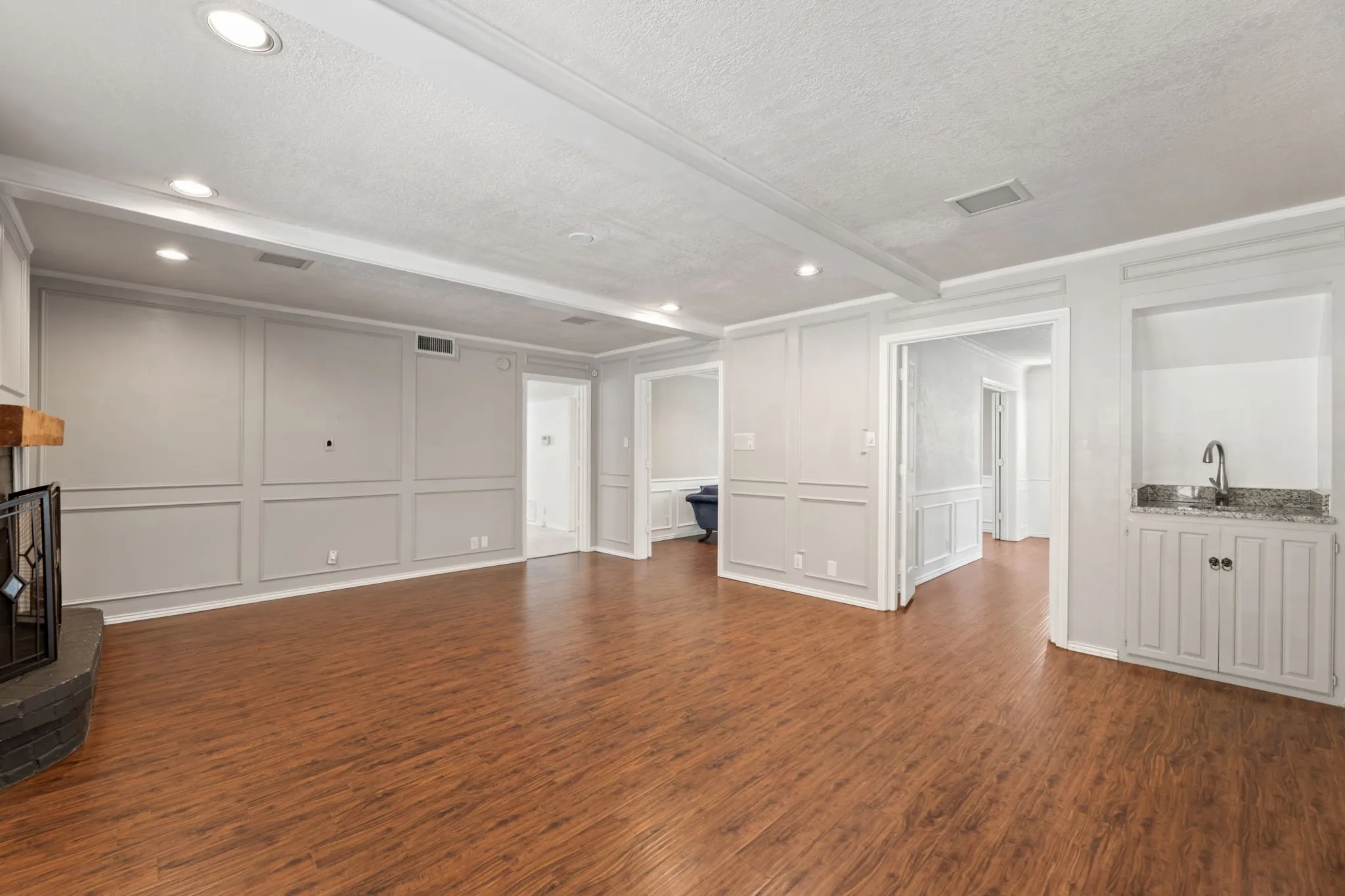 Unfurnished living room with a decorative wall, a fireplace, dark wood-style floors, a textured ceiling, and recessed lighting