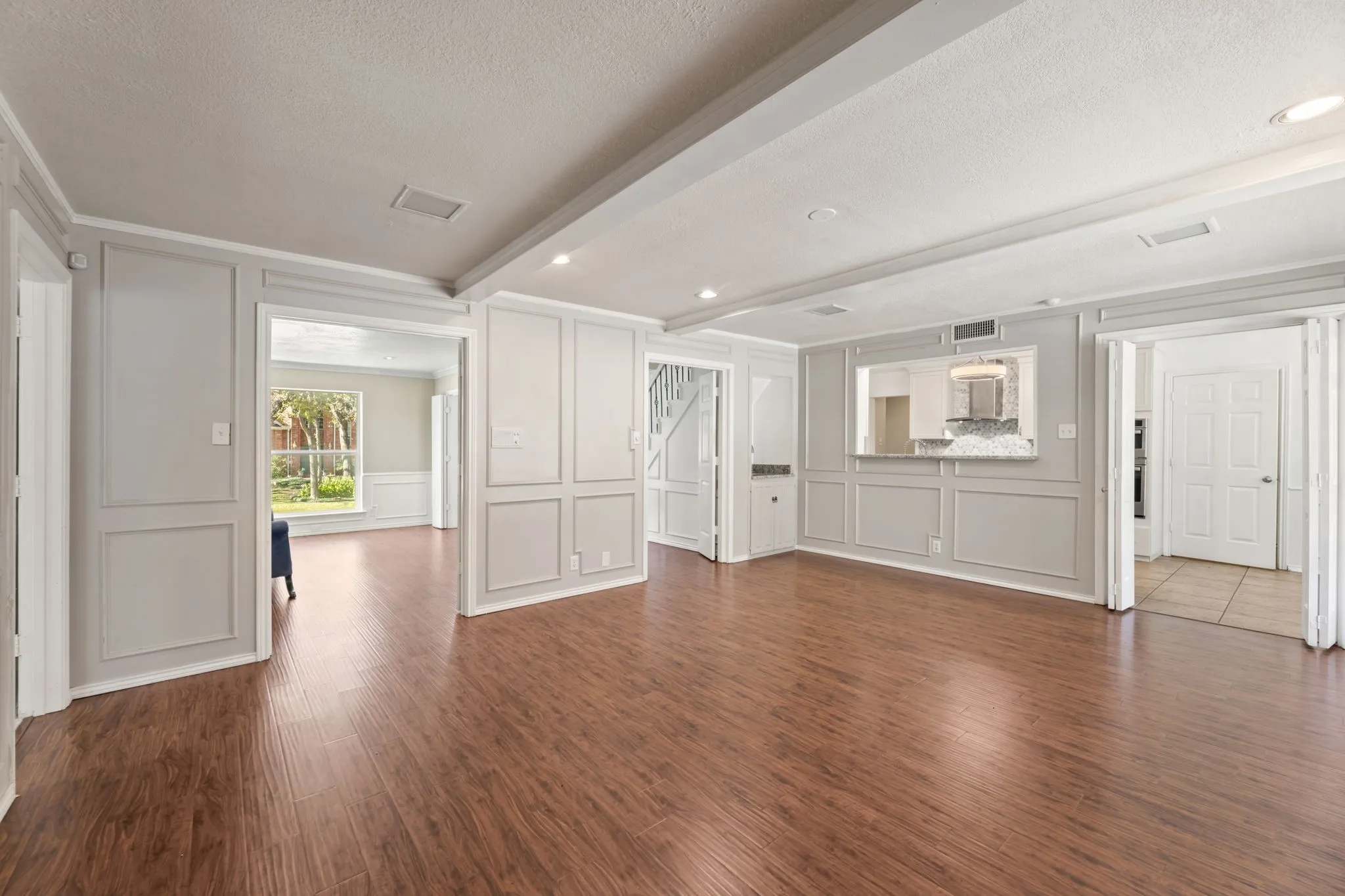 Unfurnished living room with a decorative wall, dark wood-style flooring, beam ceiling, a textured ceiling, and recessed lighting