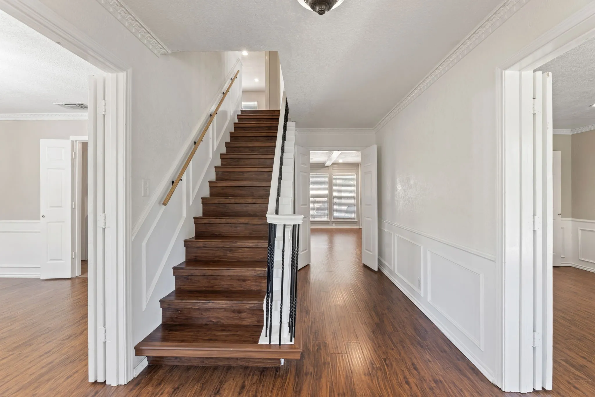Stairs featuring a wainscoted wall, wood finished floors, ornamental molding, a decorative wall, and a textured ceiling