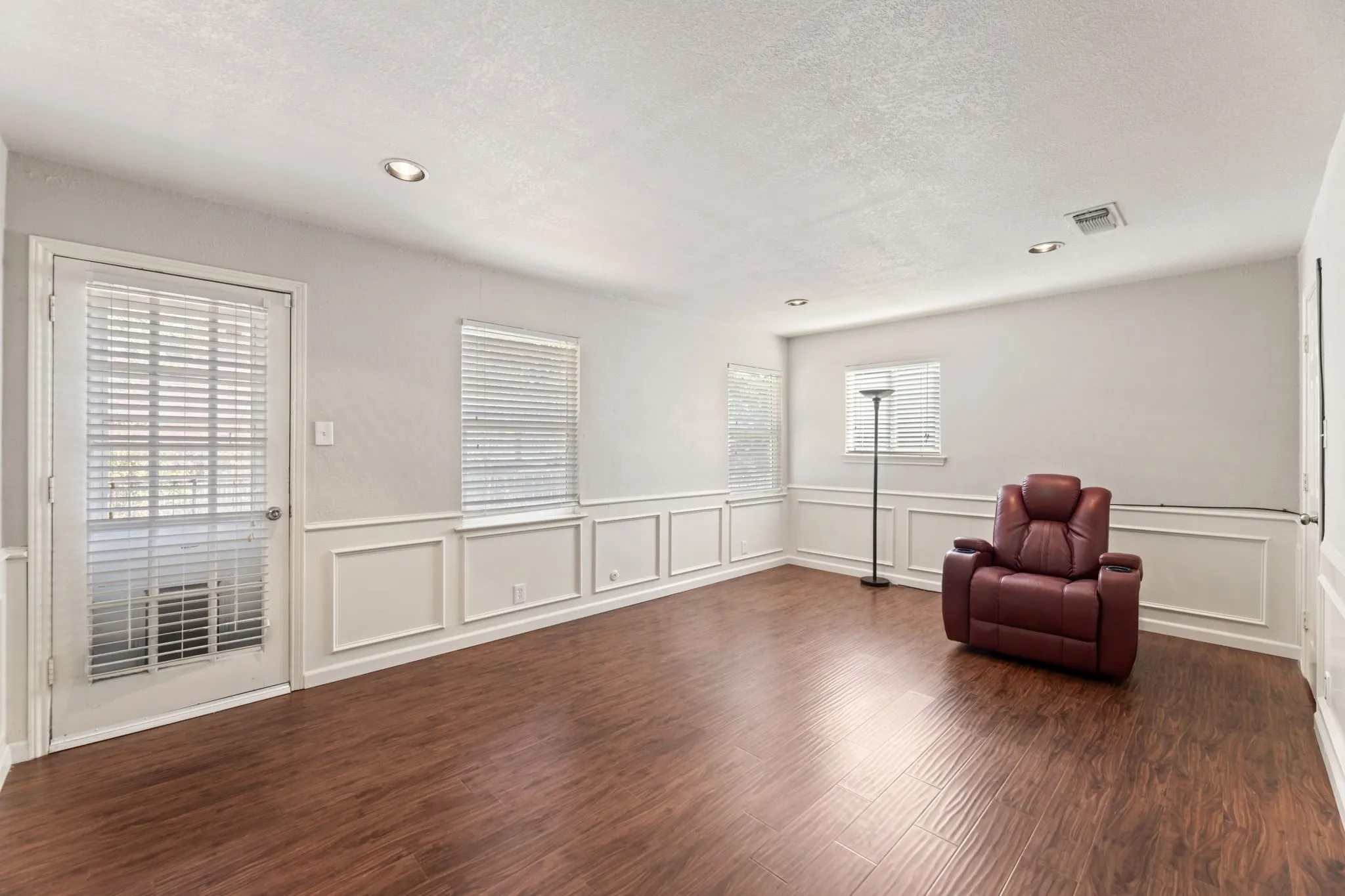 Unfurnished room featuring dark wood-style floors, a textured ceiling, recessed lighting, a decorative wall, and a wainscoted wall
