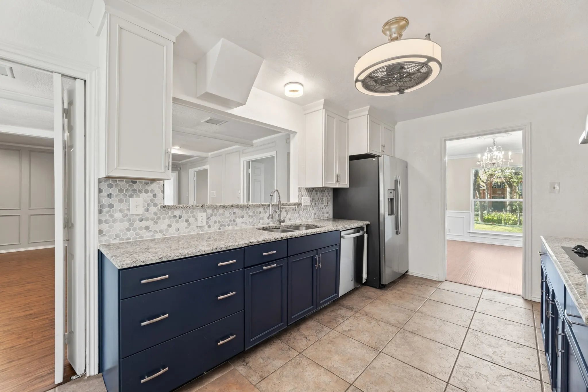 Kitchen featuring blue cabinets, white cabinets, tasteful backsplash, light stone countertops, and a decorative wall
