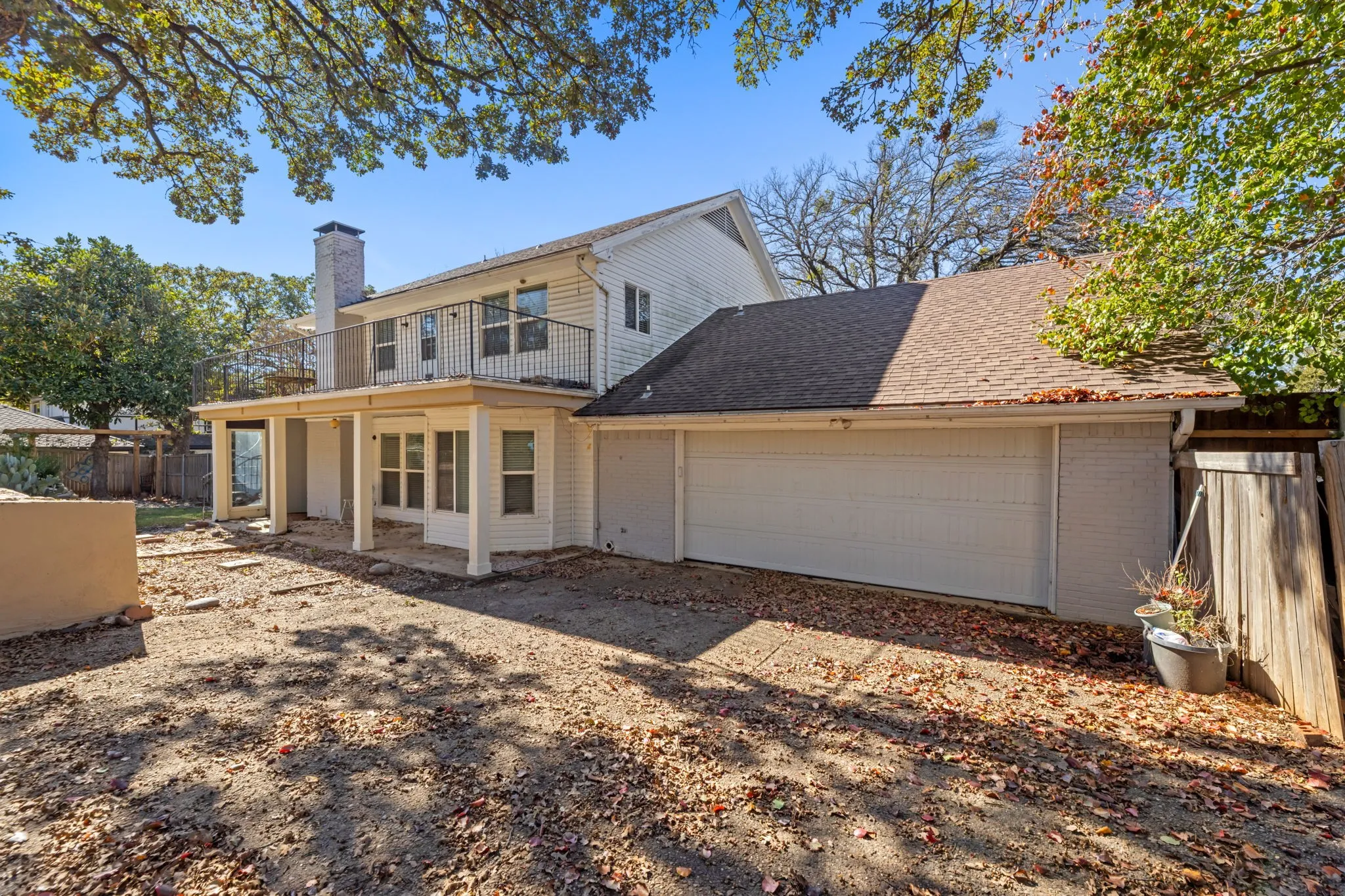 Back of property with brick siding, a chimney, an attached garage, a shingled roof, and a patio