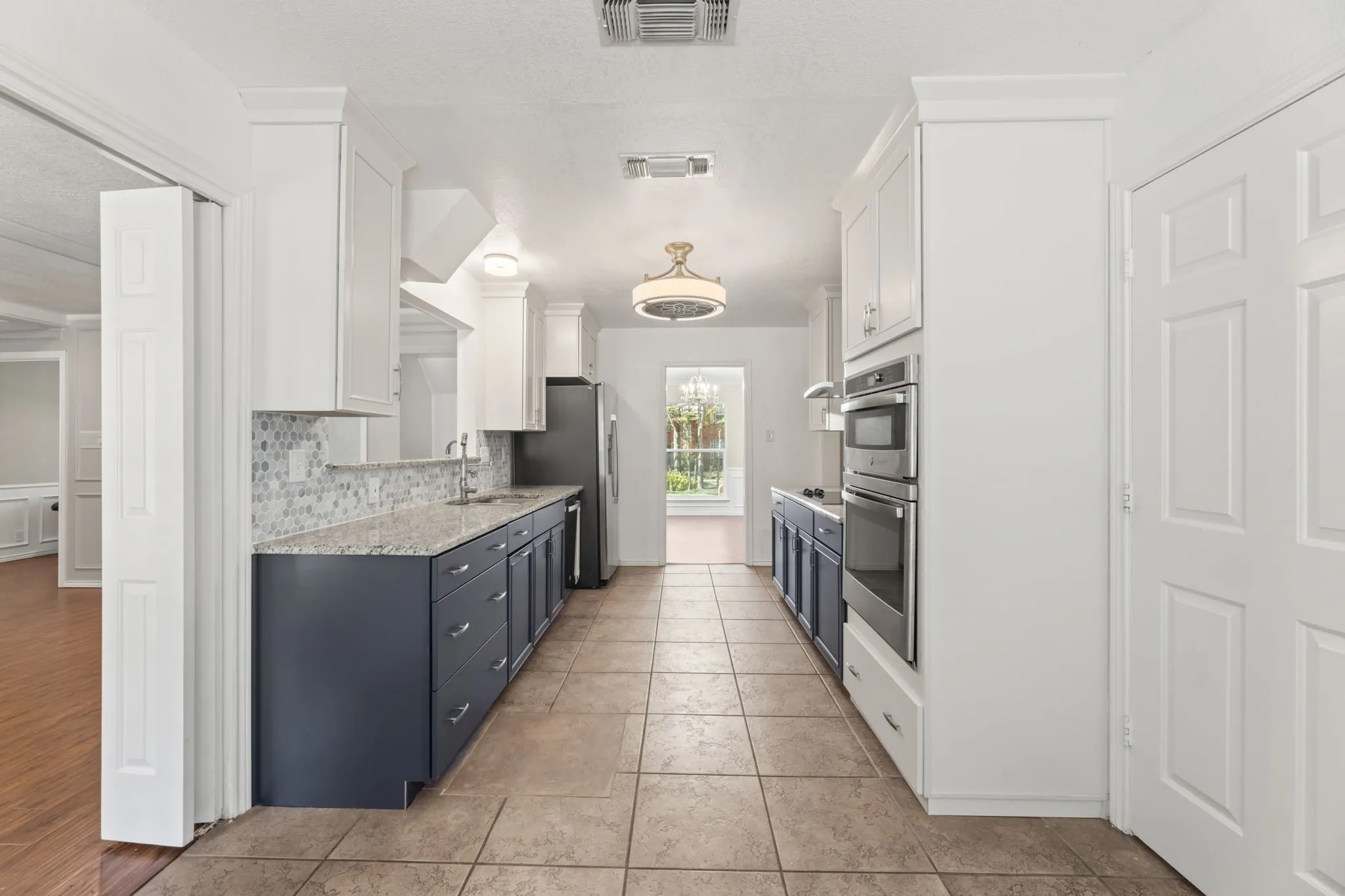 Kitchen with white cabinets, tasteful backsplash, blue cabinetry, appliances with stainless steel finishes, and a textured ceiling