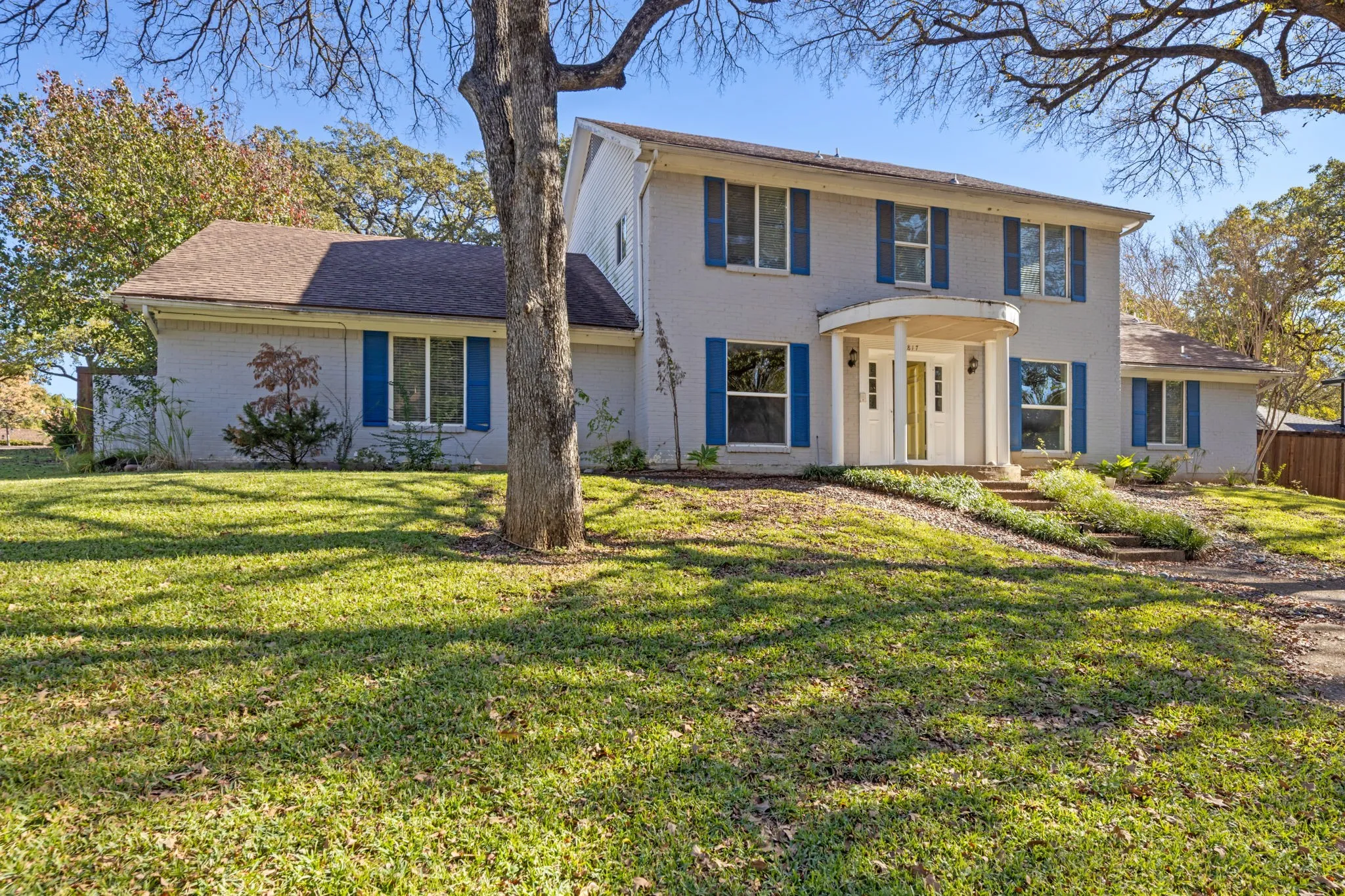 View of front of house with brick siding, a front yard, and roof with shingles