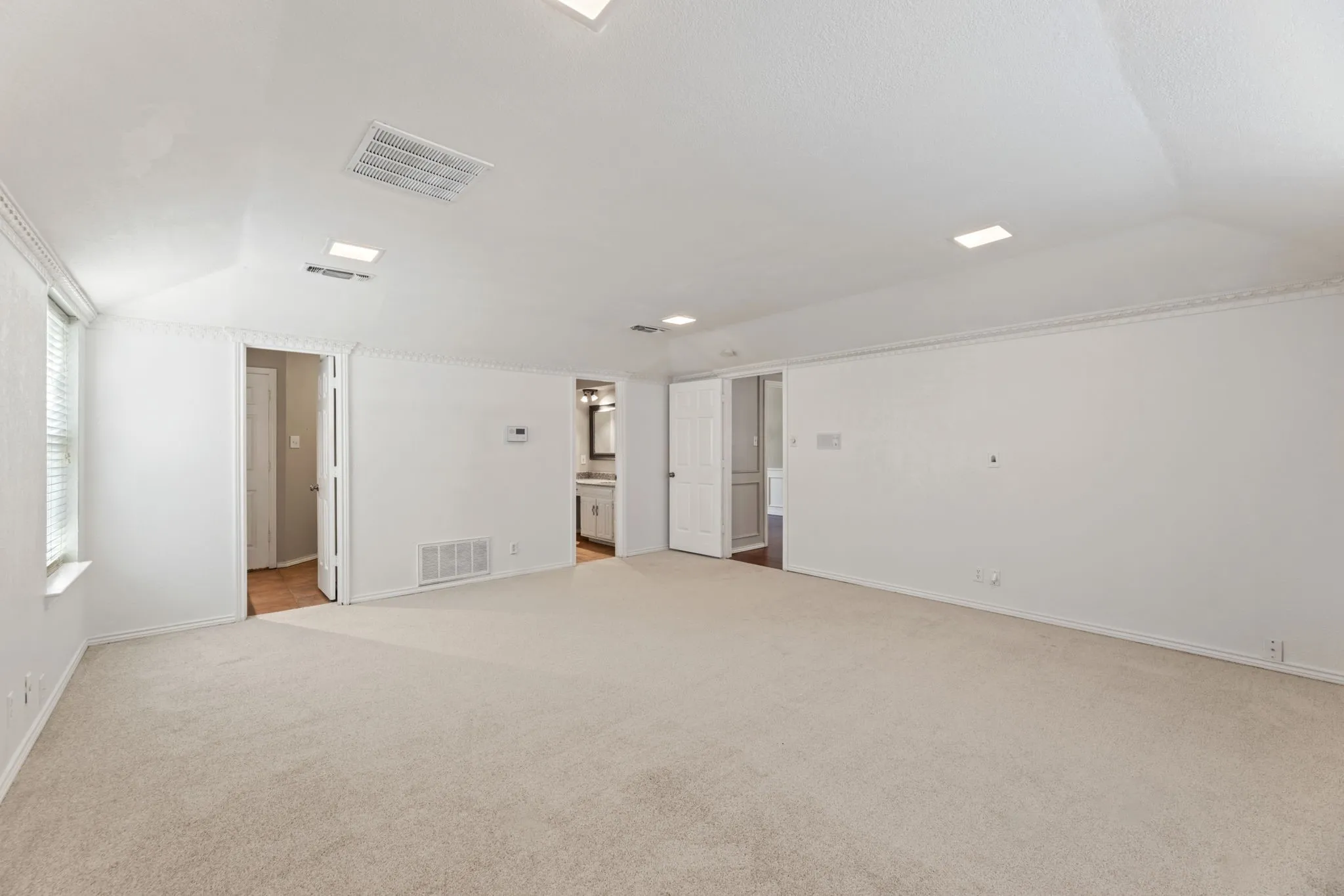 Empty room featuring light carpet and vaulted ceiling