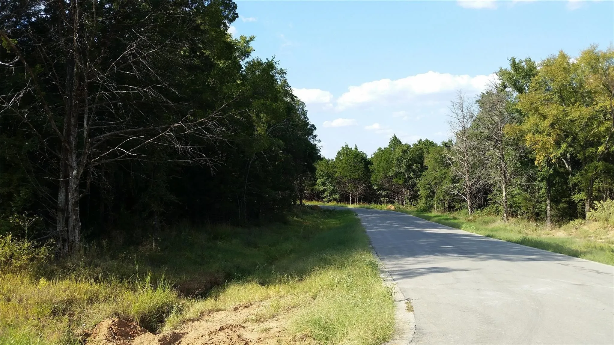 View of asphalt street featuring a view of trees