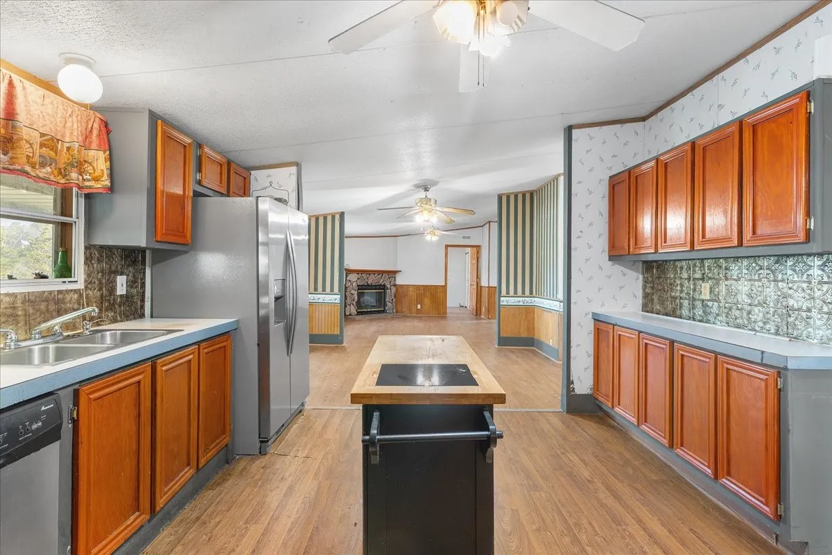 Kitchen with decorative backsplash, wainscoting, stainless steel appliances, a kitchen island, and light wood finished floors