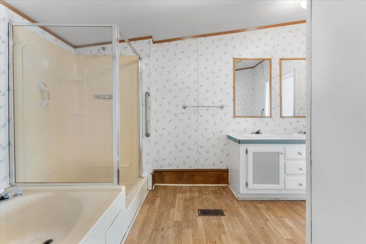 Full bathroom with vanity, light wood finished floors, wallpapered walls, a shower, and a tub to relax in