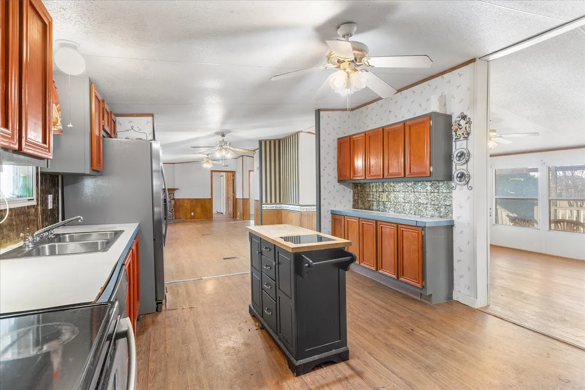 Kitchen with healthy amount of natural light, range with electric cooktop, a kitchen island, wainscoting, and ceiling fan