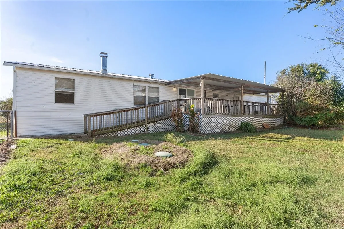 Rear view of house featuring a lawn, a deck, and a metal roof