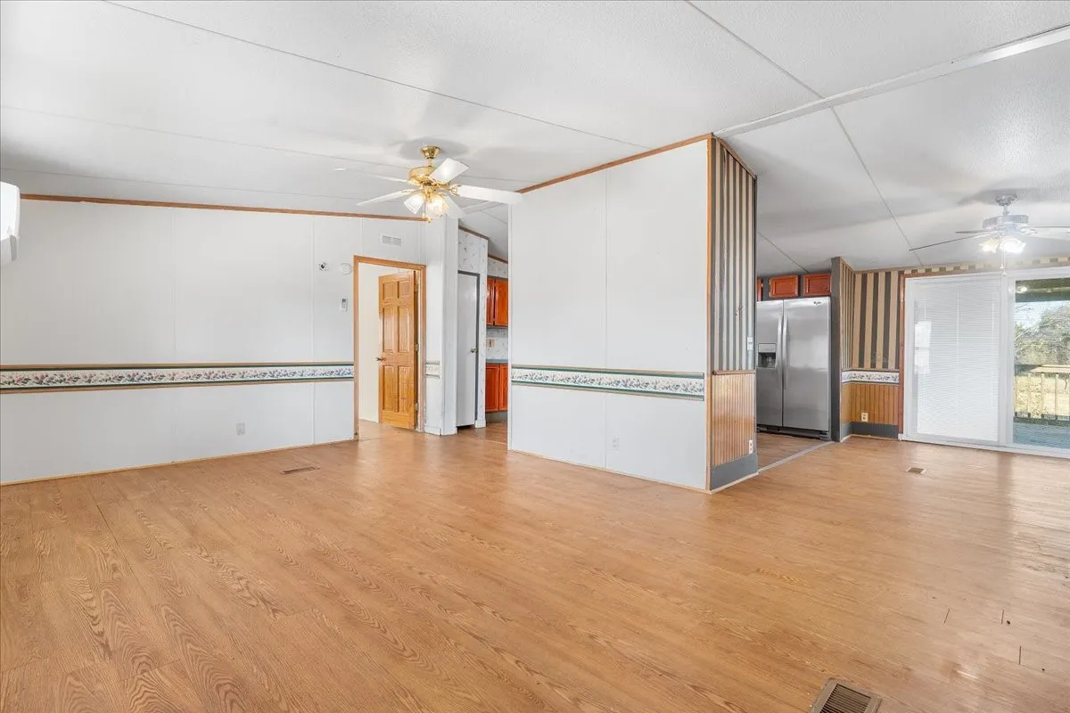 Unfurnished living room with ceiling fan, light wood finished floors, and lofted ceiling