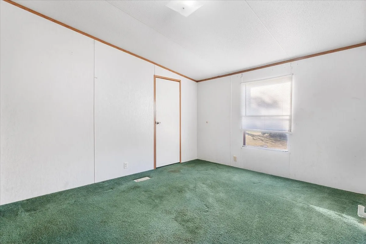 Carpeted empty room featuring lofted ceiling and ornamental molding