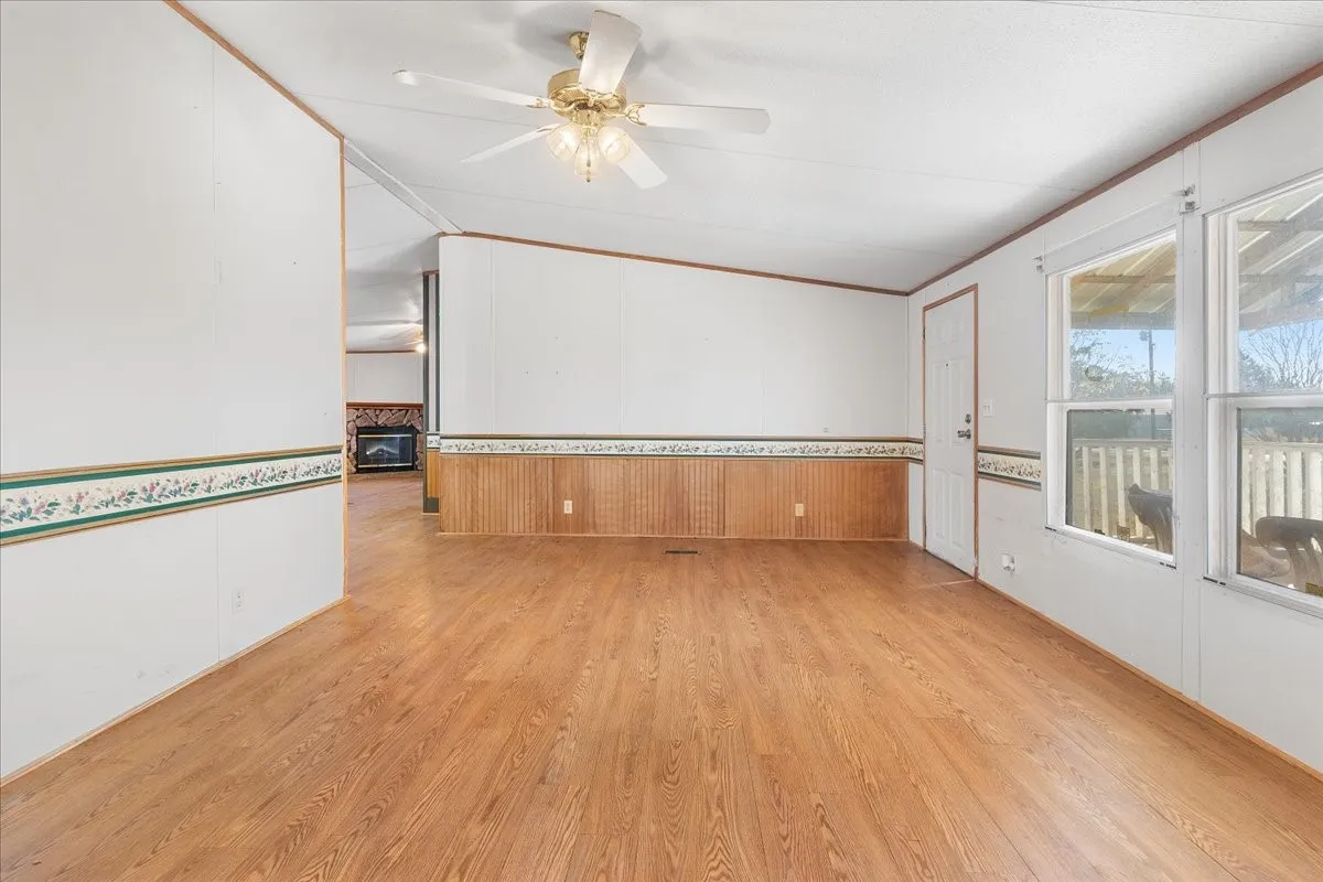 Spare room with vaulted ceiling, light wood finished floors, crown molding, ceiling fan, and a fireplace