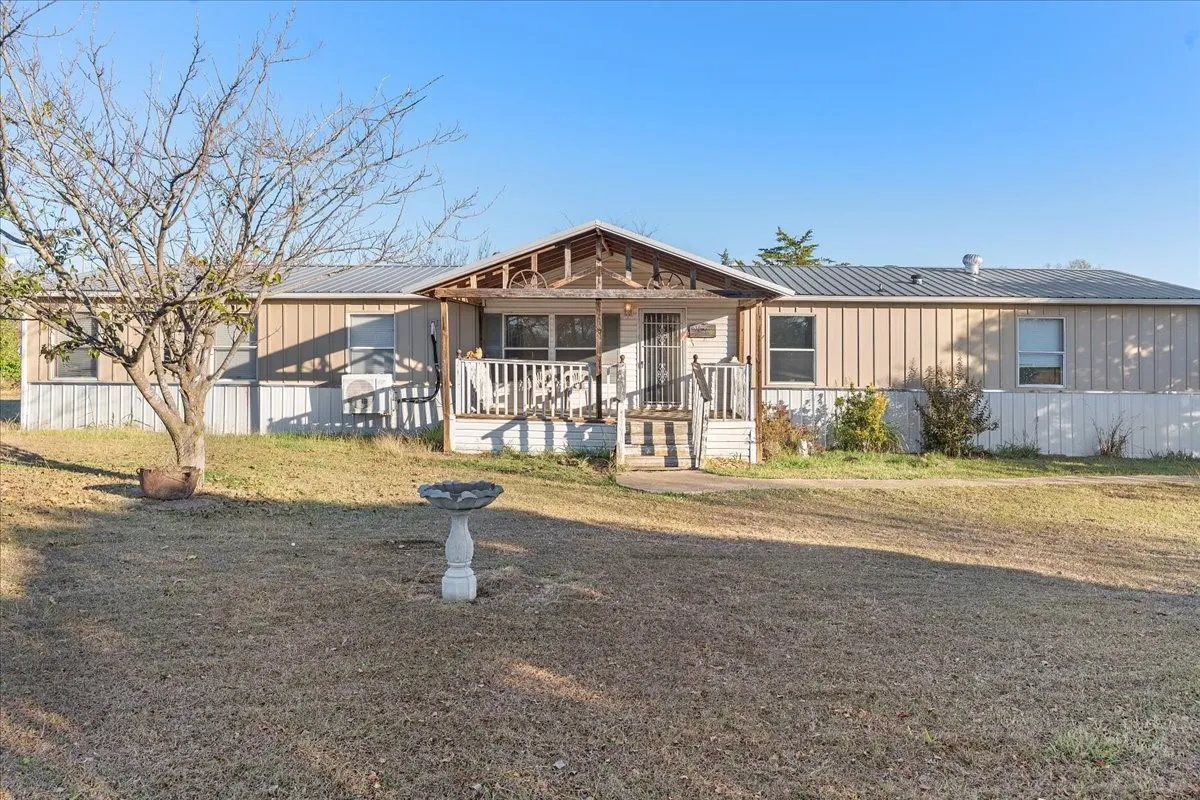 View of front of house featuring a porch, board and batten siding, a front lawn, and a metal roof