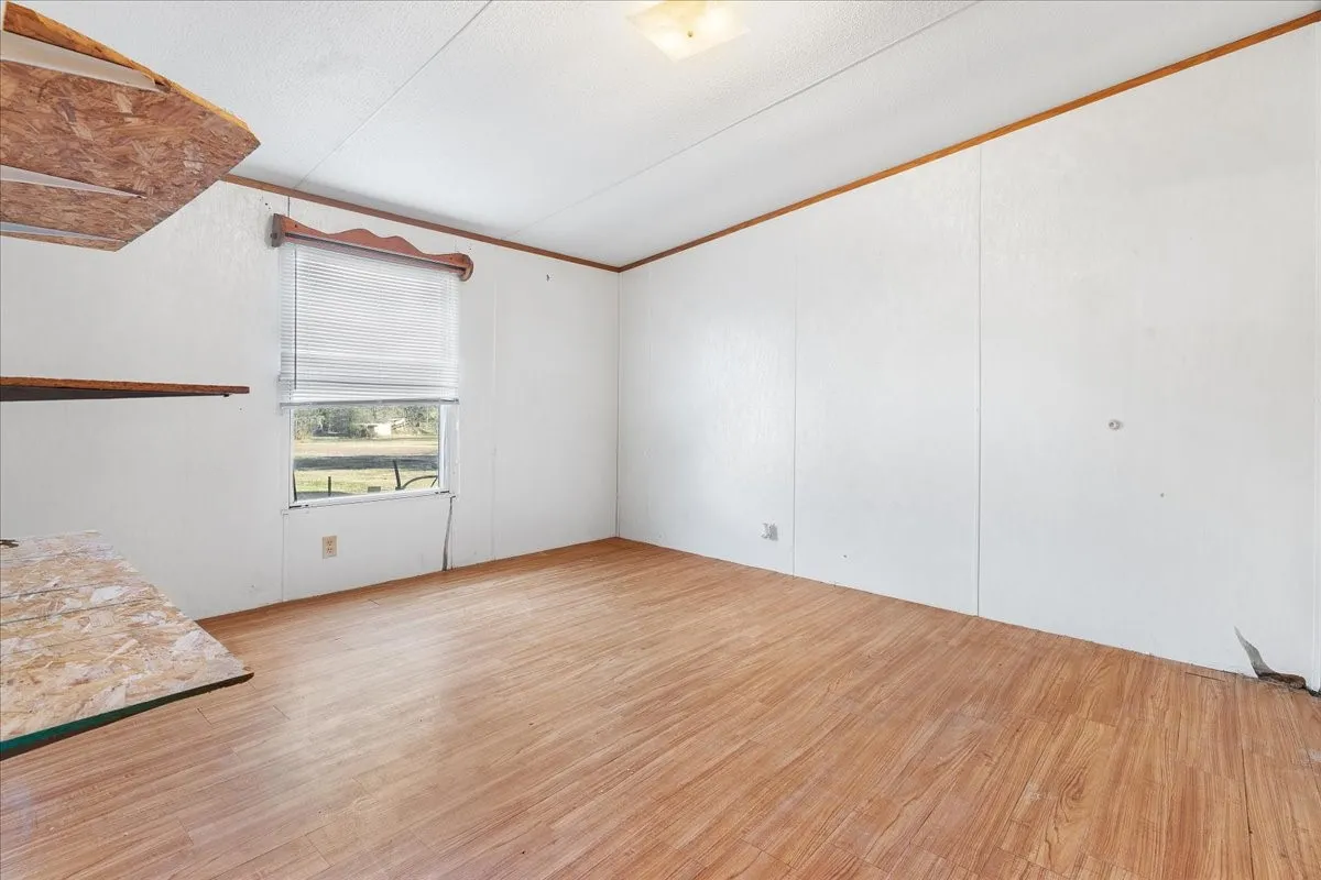 Unfurnished room featuring light wood-style floors and vaulted ceiling