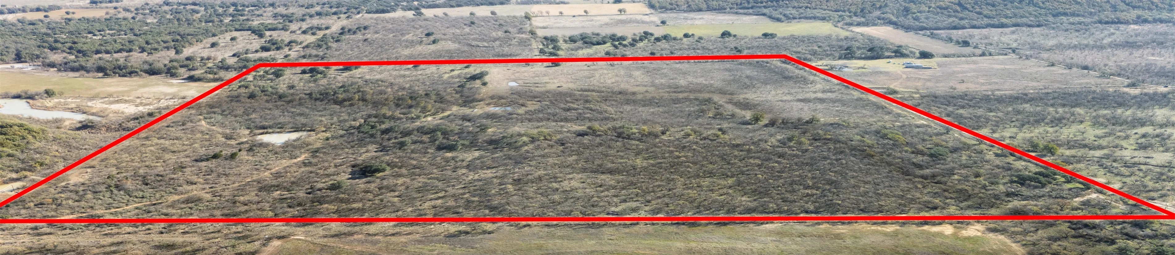 Aerial view of sparsely populated area featuring property parcel outlined and a heavily wooded area