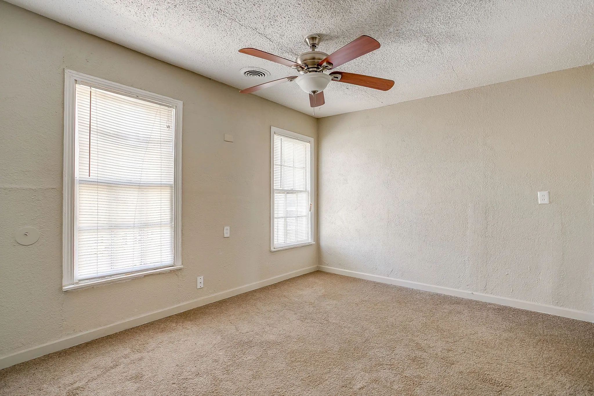 Spare room with a textured wall, light colored carpet, a ceiling fan, and a textured ceiling