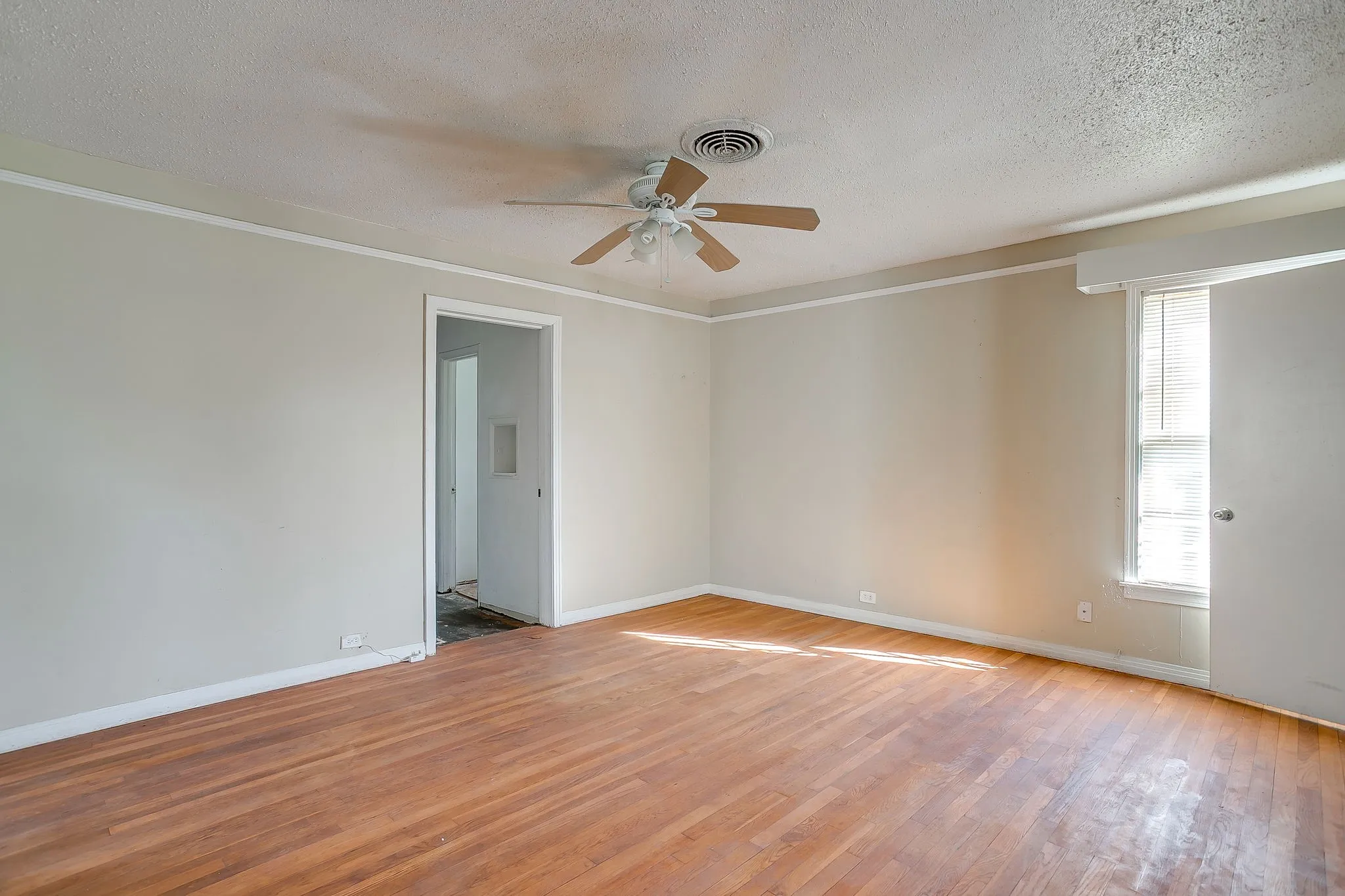 Empty room featuring a textured ceiling, light wood-style floors, and a ceiling fan