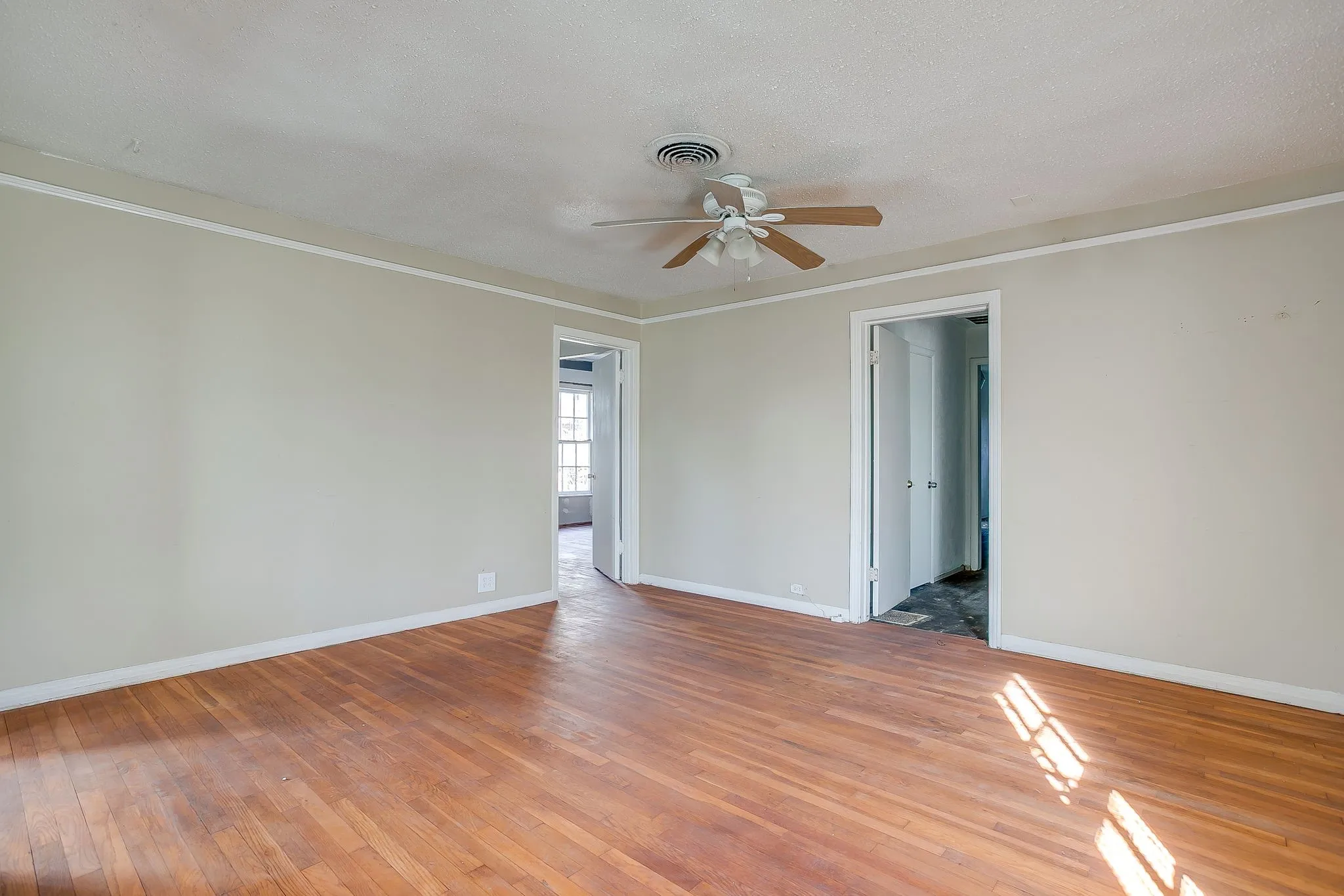 Empty room with light wood-style flooring, a textured ceiling, a ceiling fan, and ornamental molding