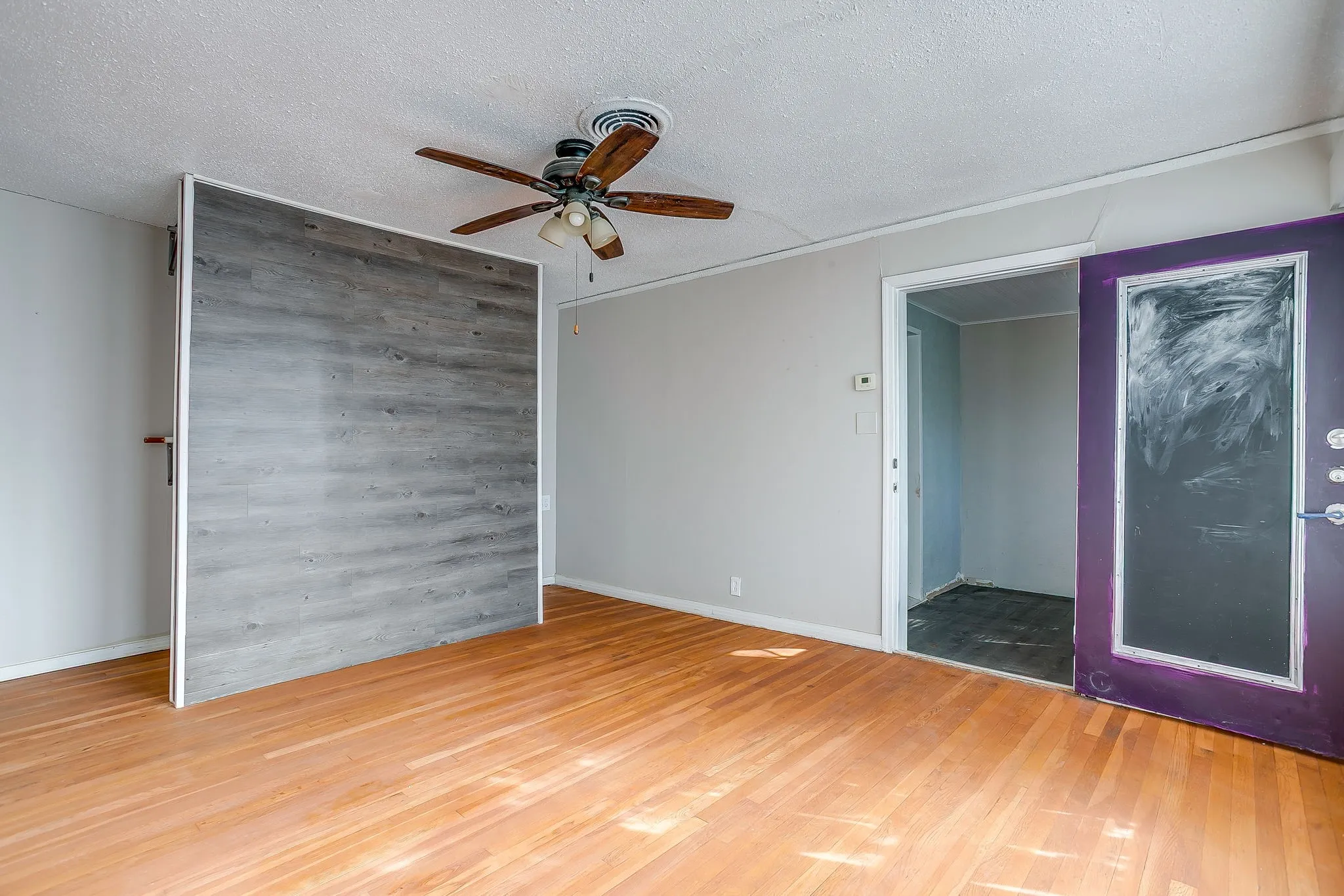 Spare room with a textured ceiling, wood finished floors, a ceiling fan, wood walls, and an accent wall
