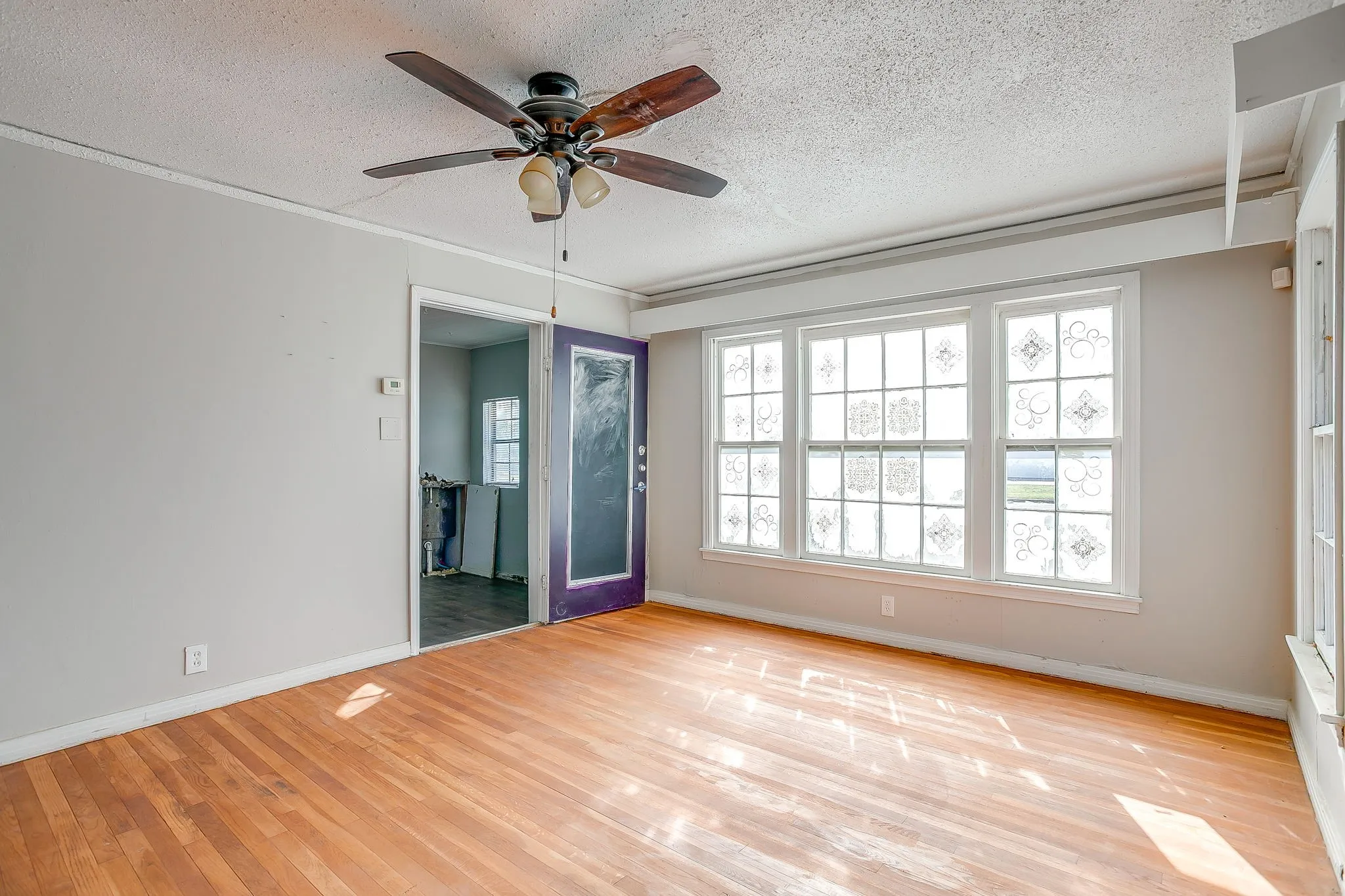 Unfurnished room featuring a textured ceiling, light wood finished floors, and a ceiling fan