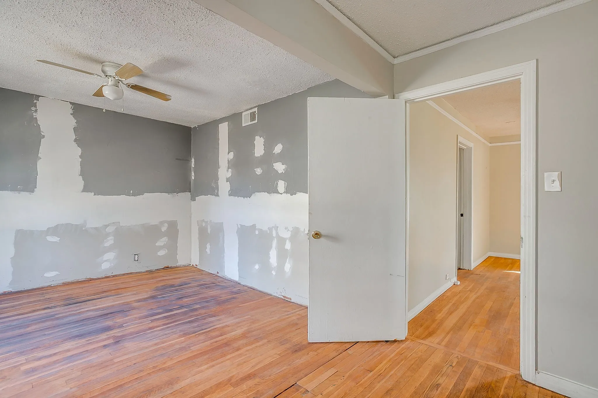 Spare room with light wood finished floors, ceiling fan, and a textured ceiling