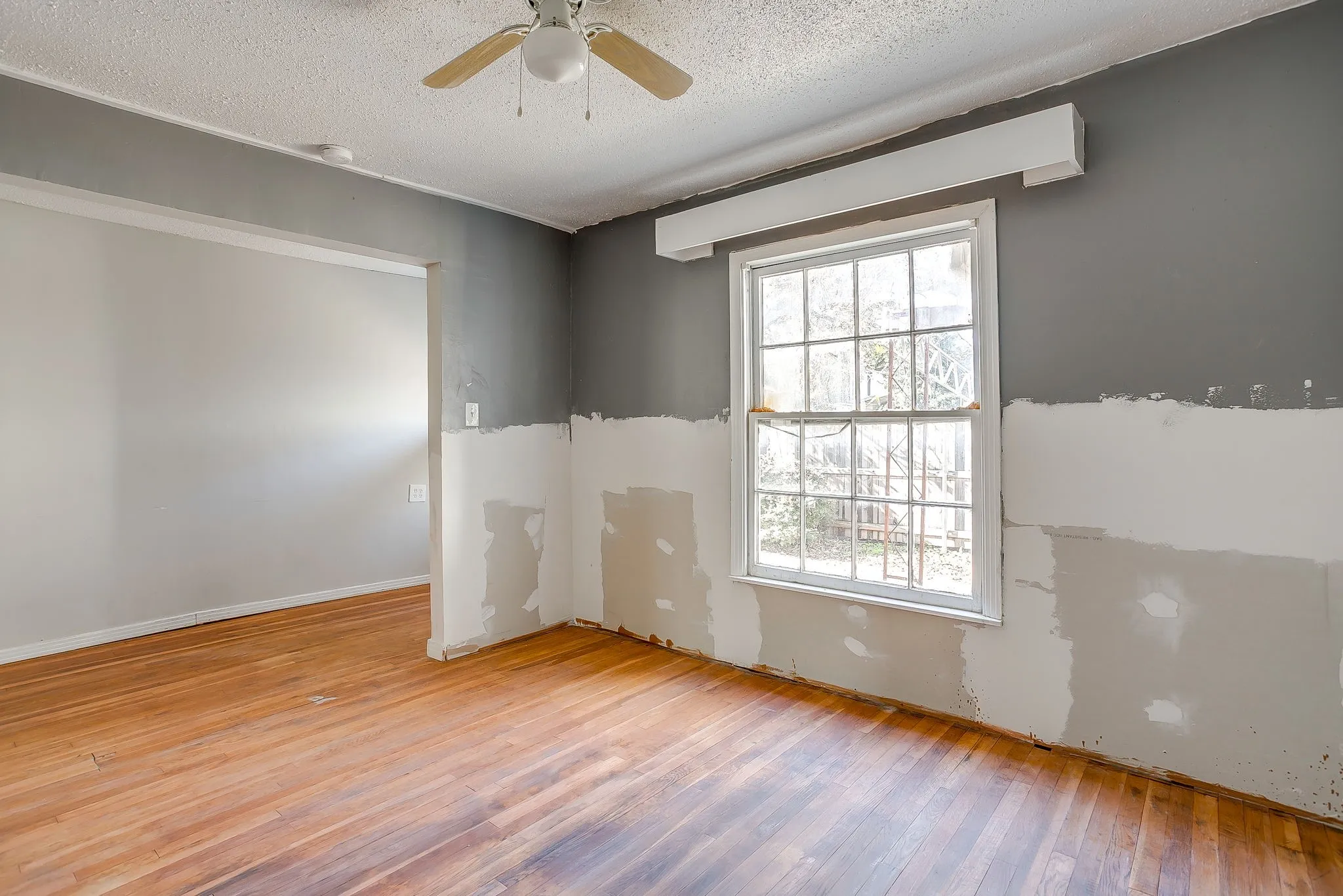 Empty room featuring a textured ceiling, light wood-style floors, and ceiling fan