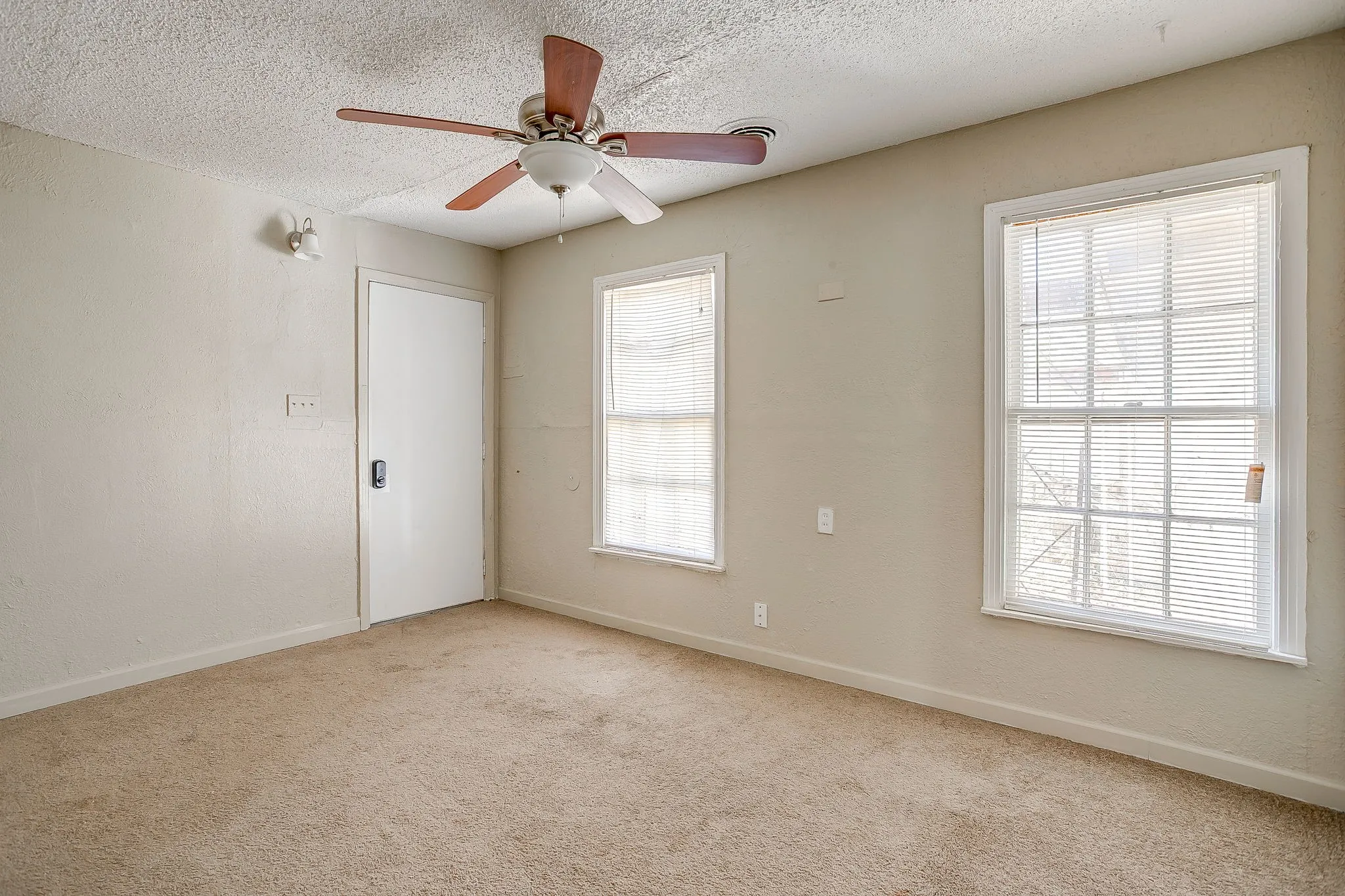 Empty room featuring a textured ceiling, carpet flooring, and a ceiling fan
