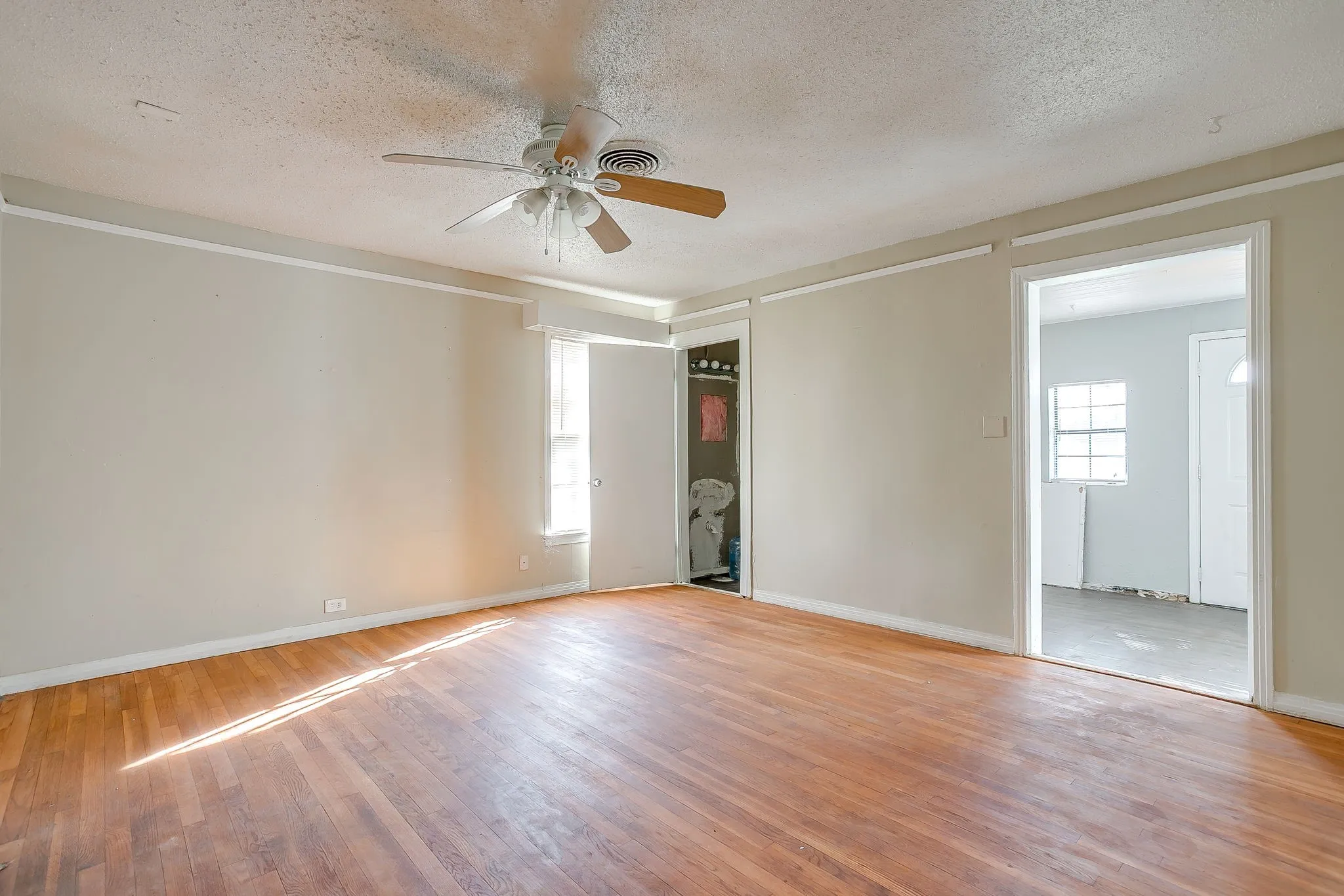 Unfurnished room featuring a textured ceiling, wood-type flooring, and ceiling fan