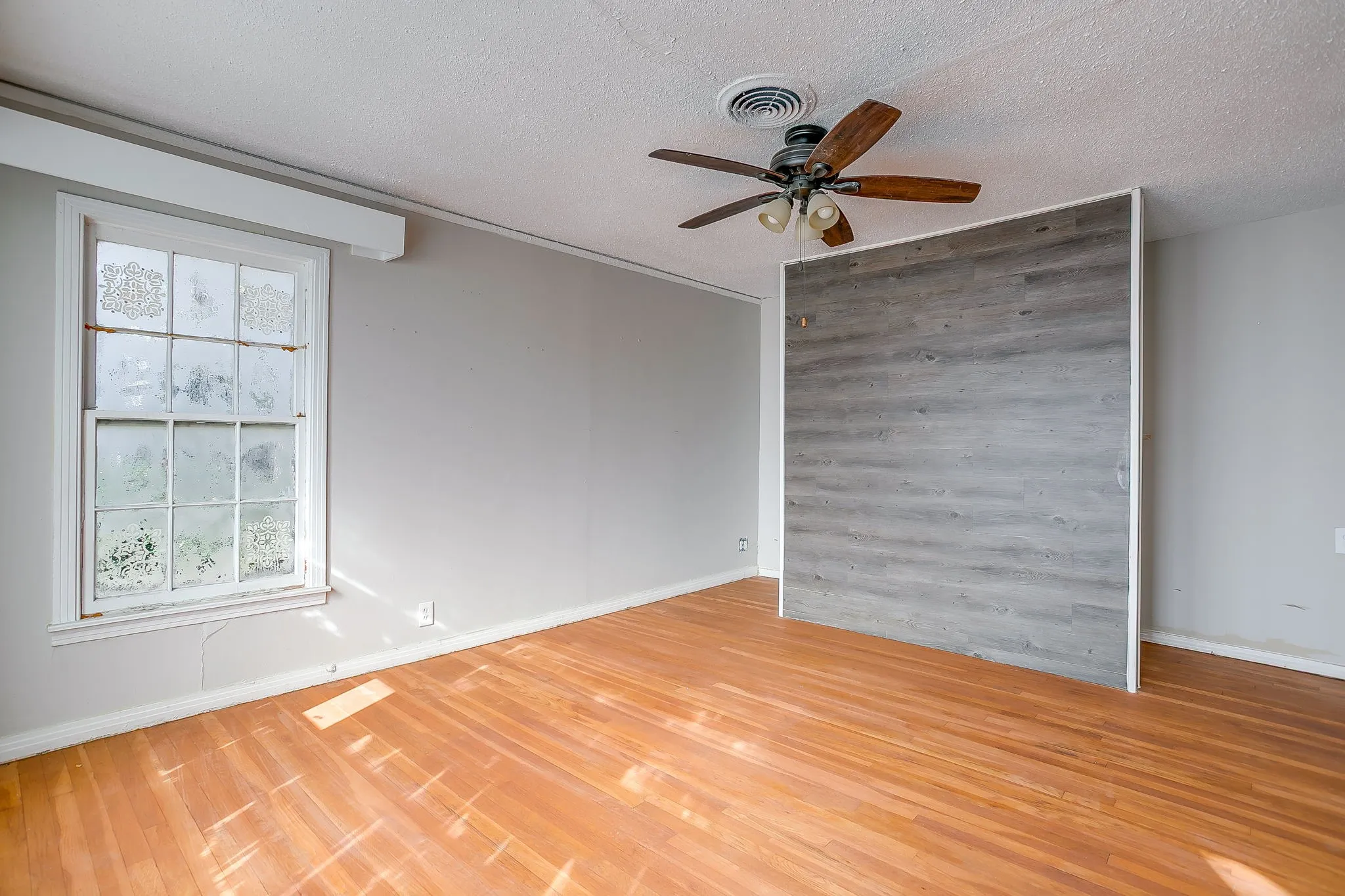 Empty room featuring light wood finished floors, a textured ceiling, and ceiling fan