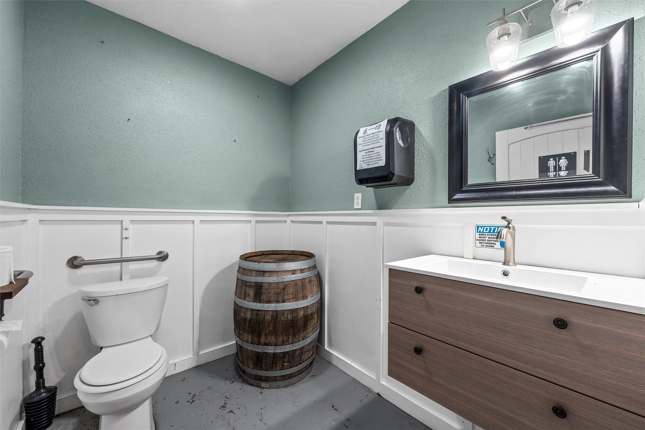 Bathroom featuring a wainscoted wall, a decorative wall, vanity, a textured wall, and concrete flooring